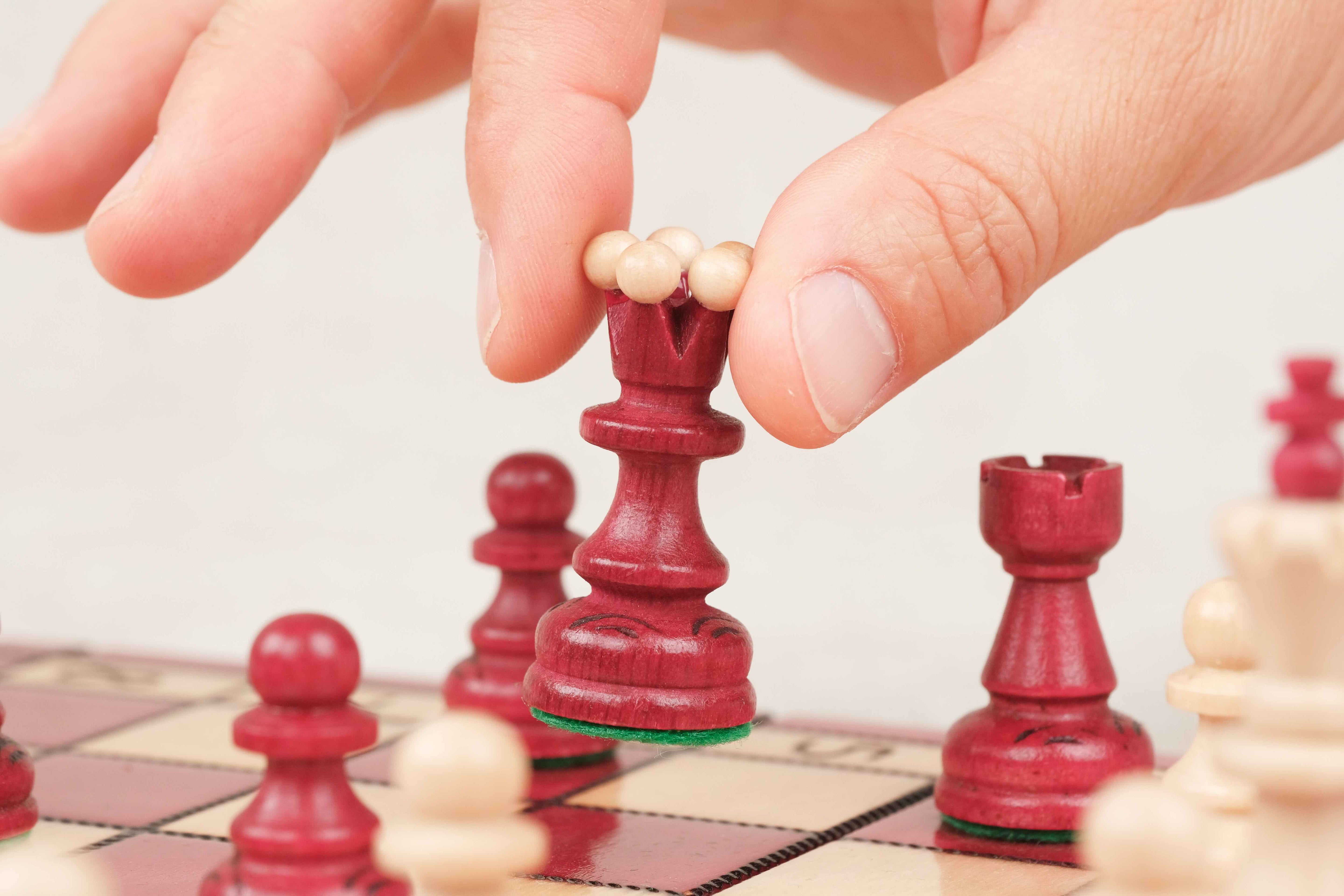 Main en train de déplacer une pièce d’échecs rouge sur le plateau
