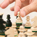 Main jouant une partie sur un plateau d’échecs en bois vert