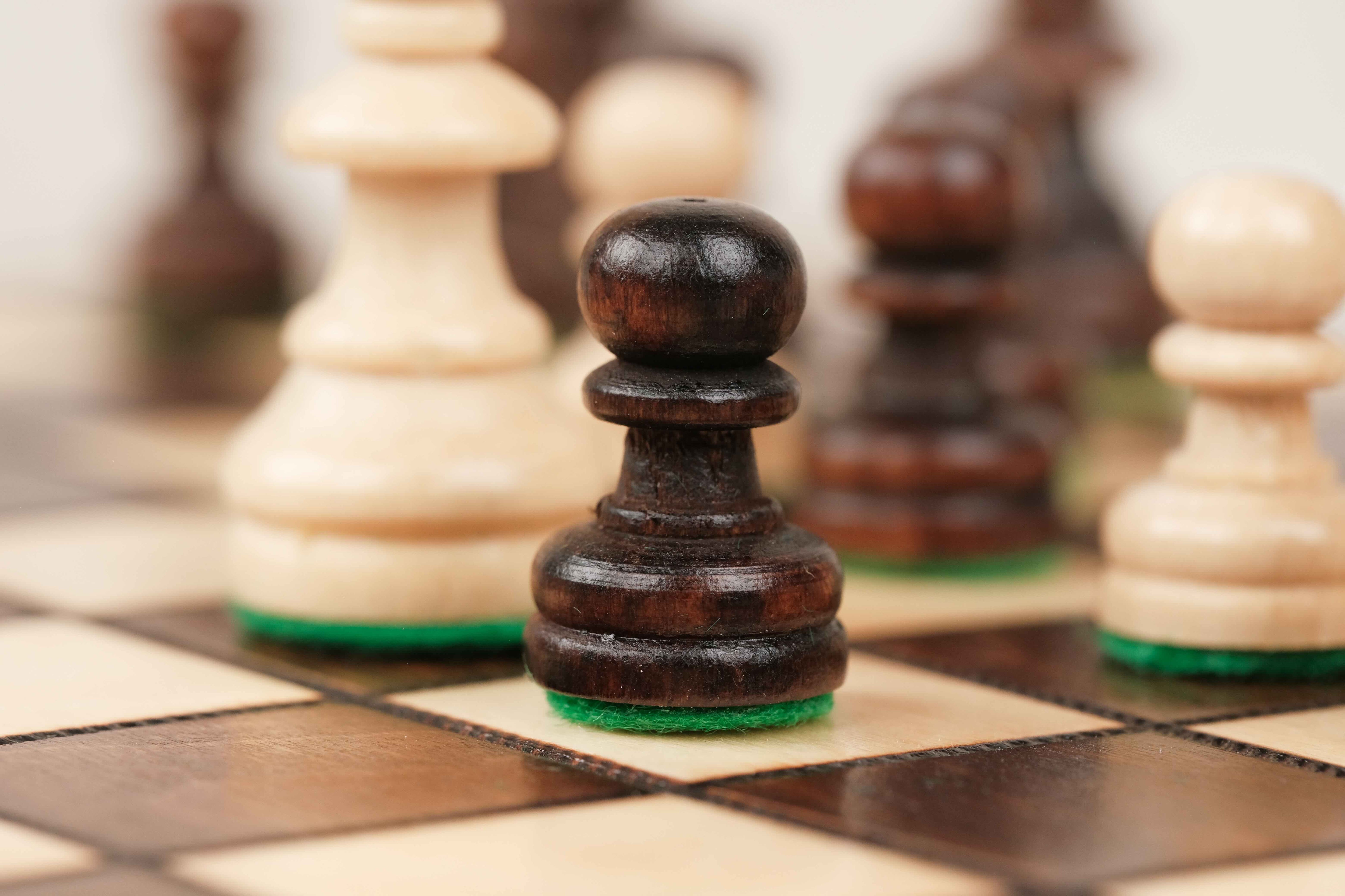 Pion d’échecs marron sur plateau en bois clair et foncé