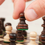 Main déplaçant une pièce d’échecs en bois marron sur plateau compact