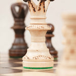 Détail d’une pièce blanc cassée (roi) sculptée sur l’échiquier