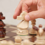 Main déplaçant un cavalier en bois sur le plateau XL