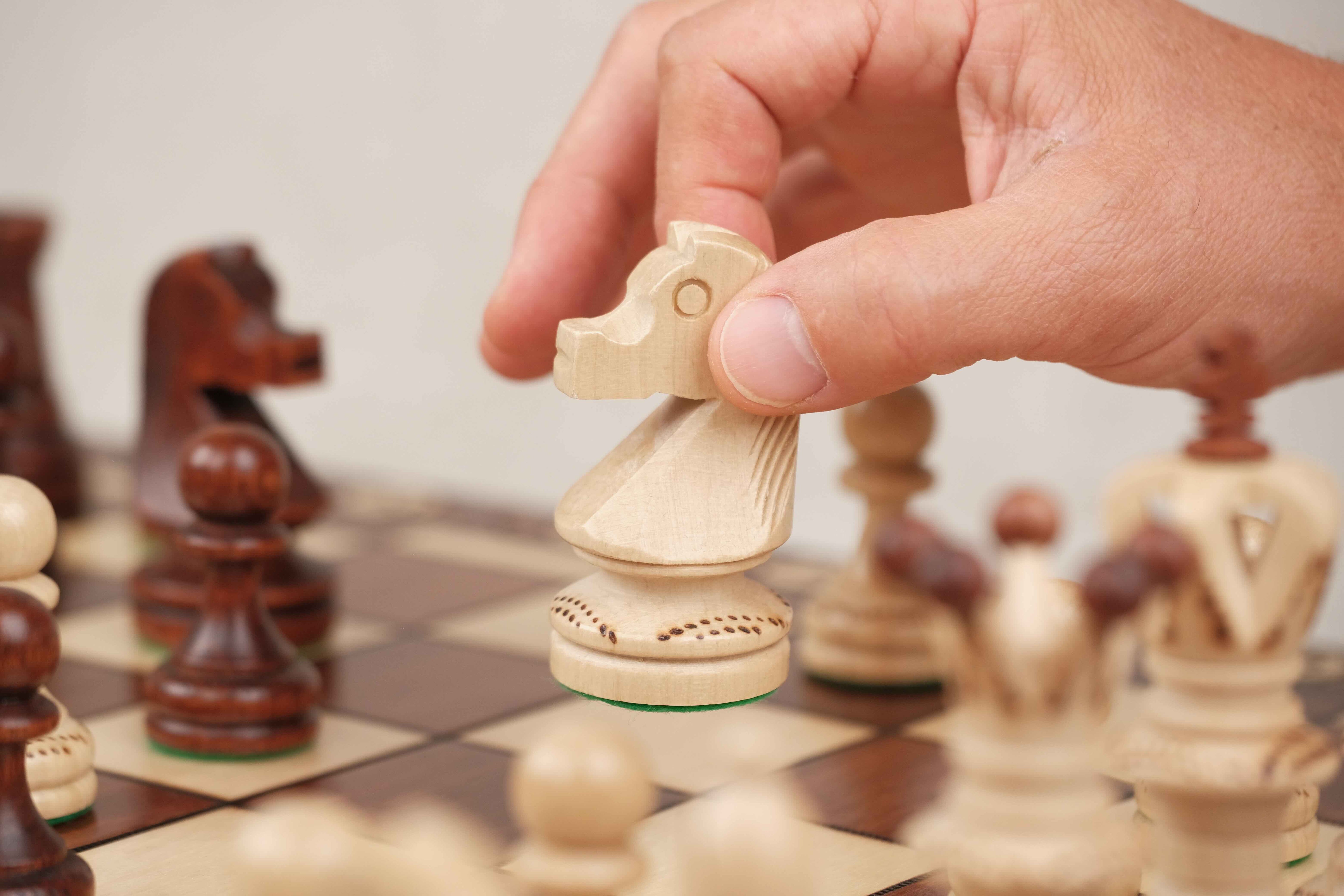Main déplaçant un cavalier en bois sur le plateau XL