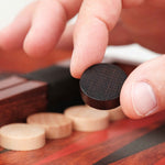 Main déplaçant un pion en bois noir sur le plateau de Backgammon