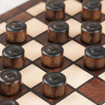 Pions de dames en bois marron et naturel sur plateau artisanal