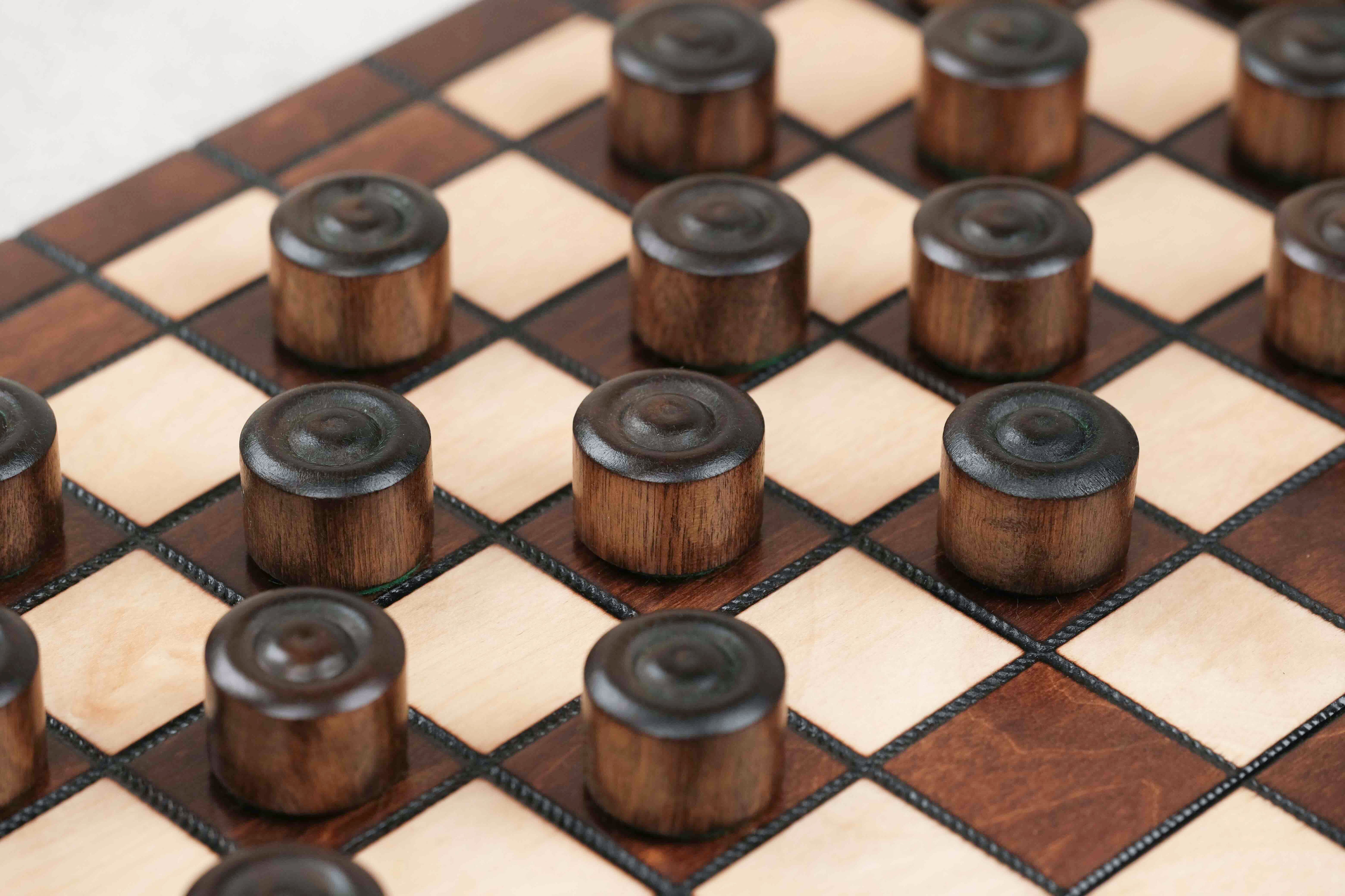 Pions de dames en bois marron et naturel sur plateau artisanal