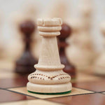 Pièce d’échecs blanche en bois avec détails sculptés sur plateau marron clair