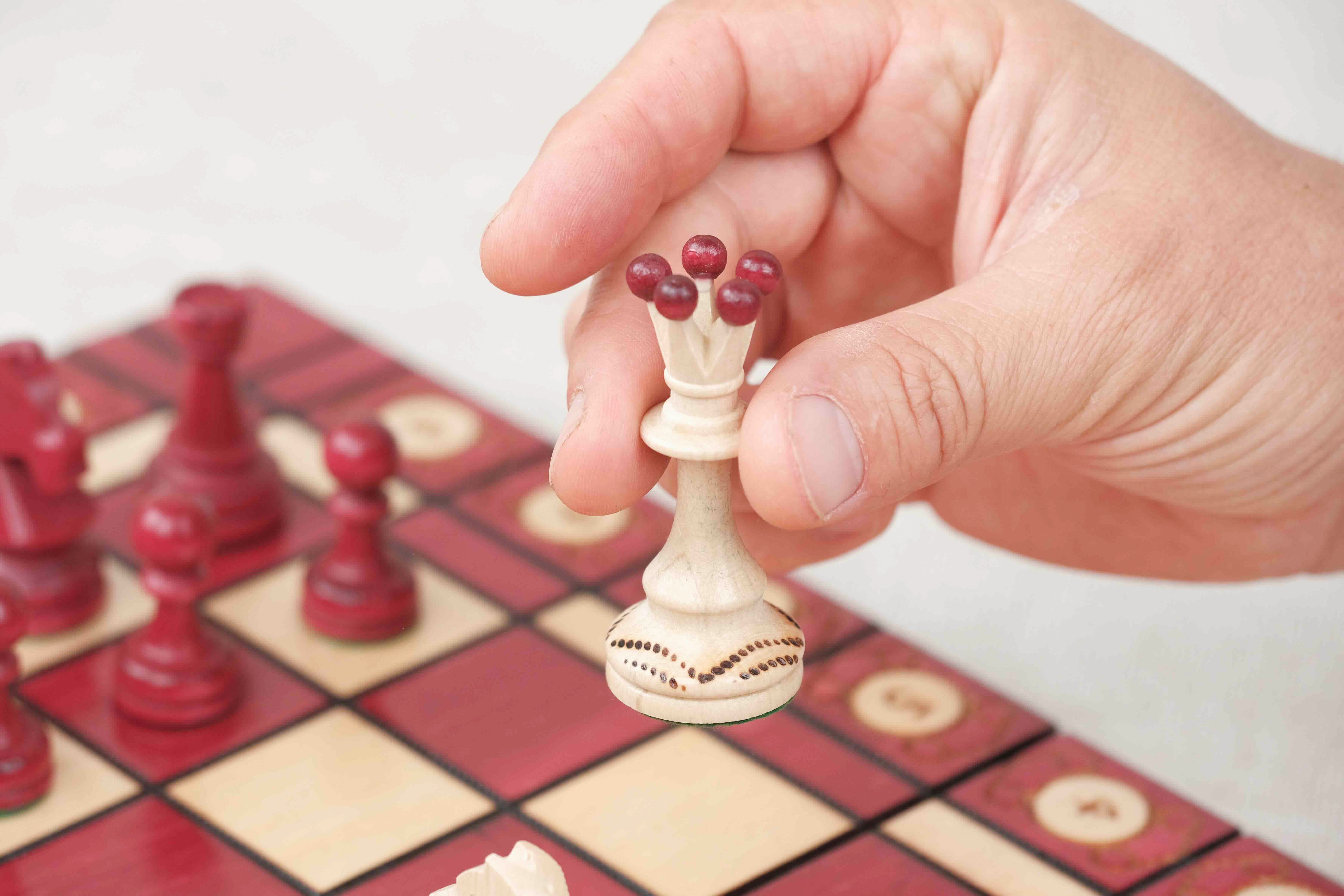 Déplacement d’une pièce d’échecs blanche sur plateau rouge grand format