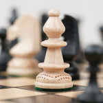 Pièce d’échecs blanche en bois avec détails sculptés sur plateau noir