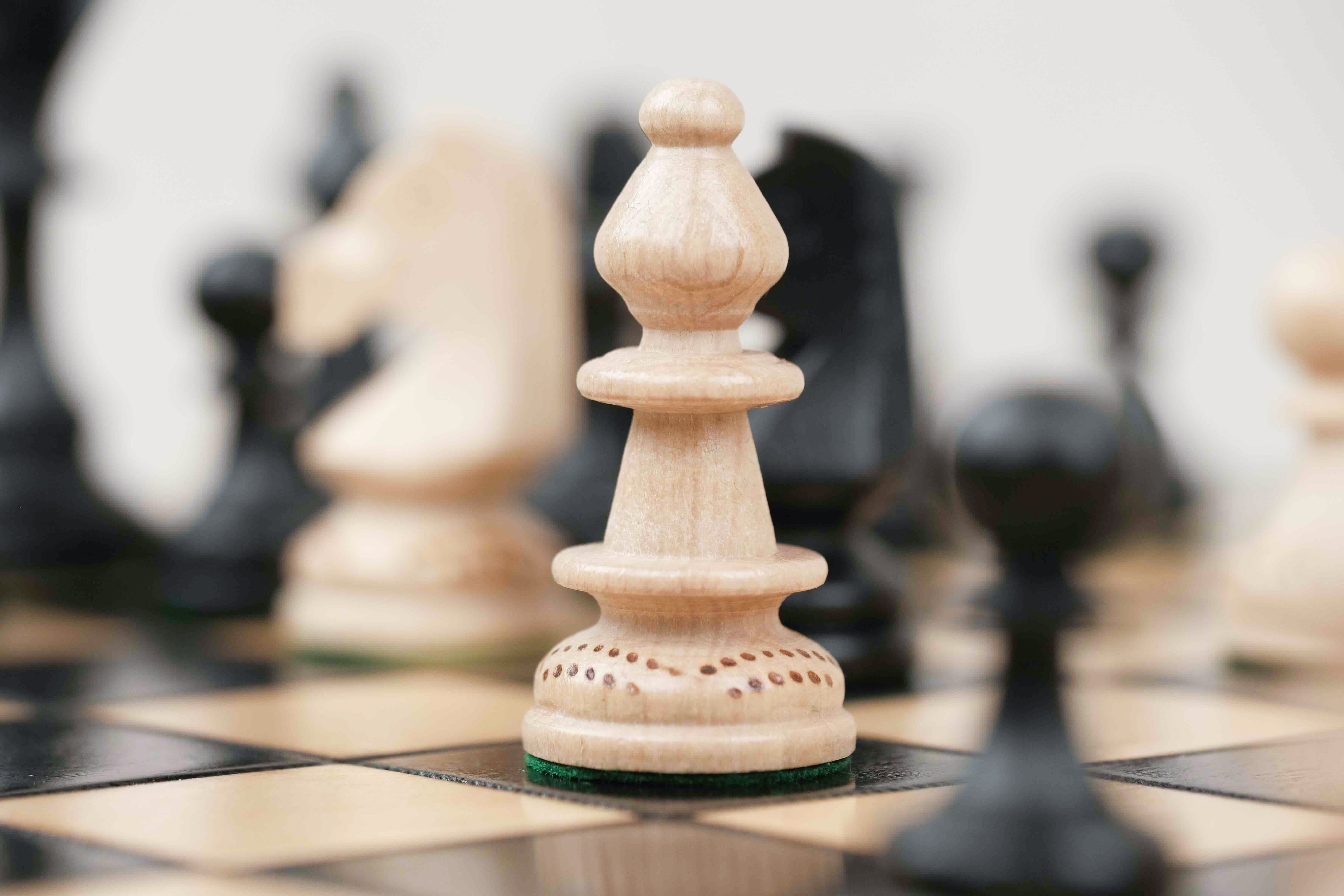 Pièce d’échecs blanche en bois avec détails sculptés sur plateau noir