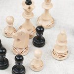 Pièces d’échecs blanche et noir en bois avec détails sculptés sur plateau noir