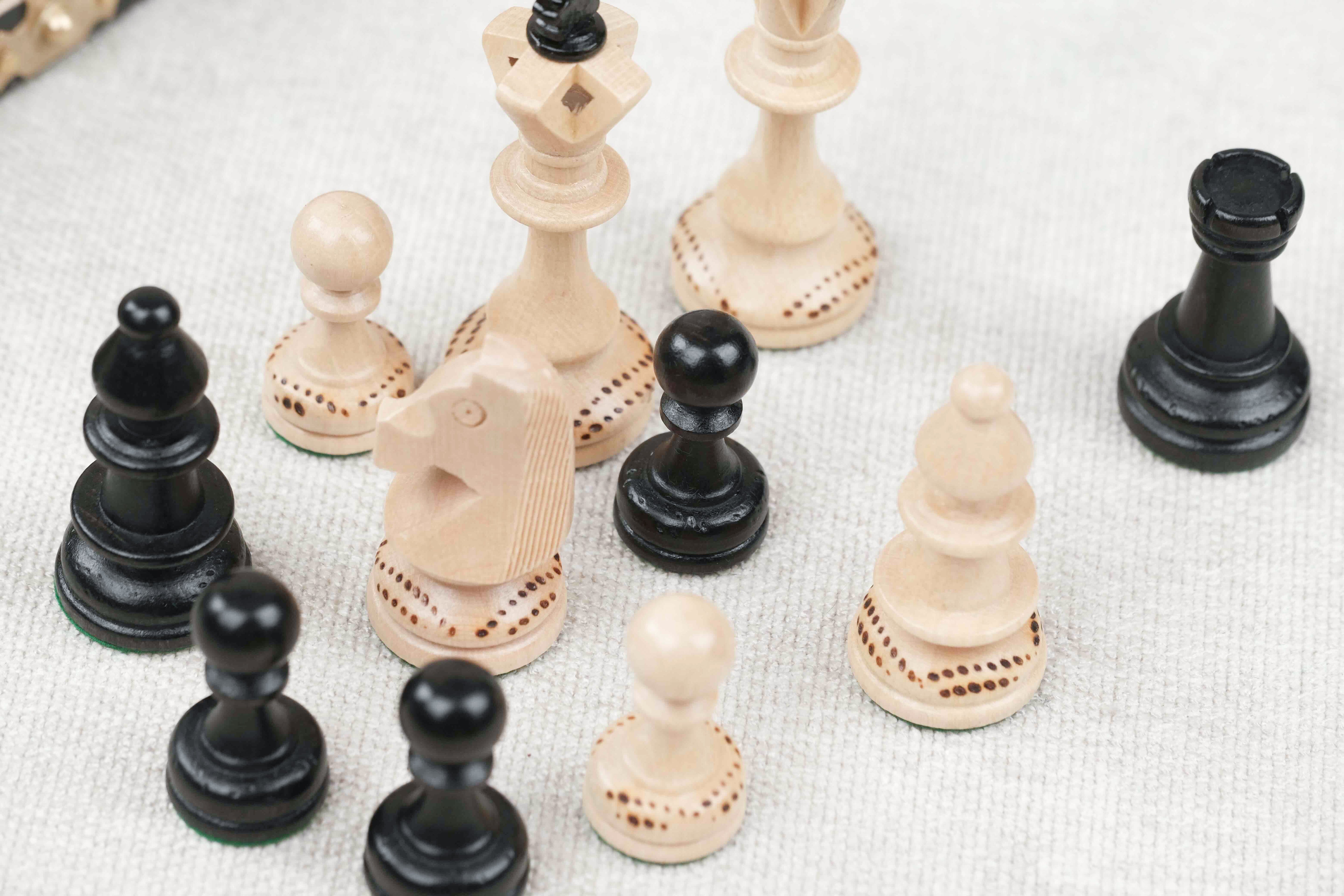 Pièces d’échecs blanche et noir en bois avec détails sculptés sur plateau noir