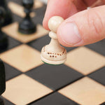 Déplacement d’un pion d’échecs blanc sur plateau en bois noir grand format