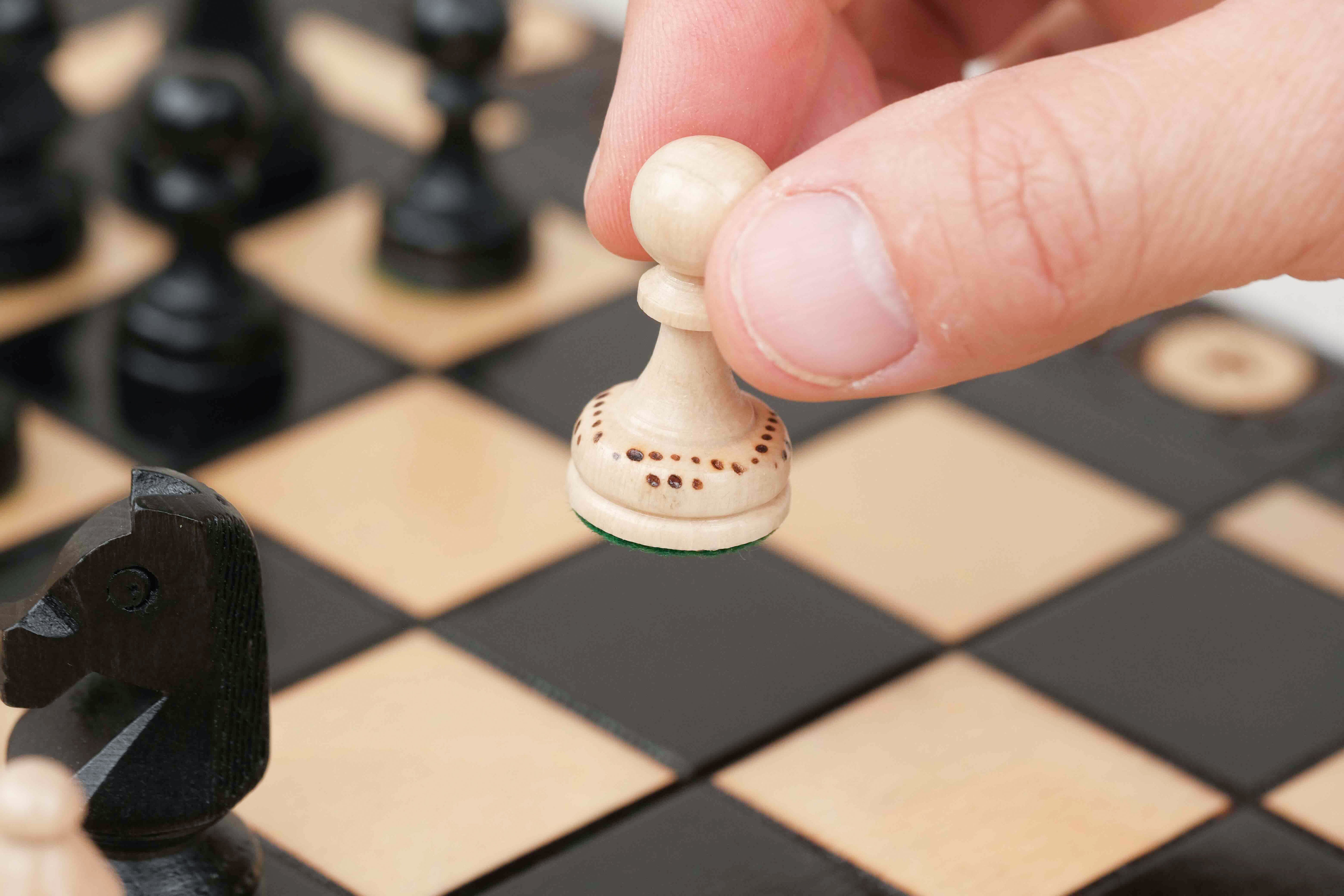 Déplacement d’un pion d’échecs blanc sur plateau en bois noir grand format
