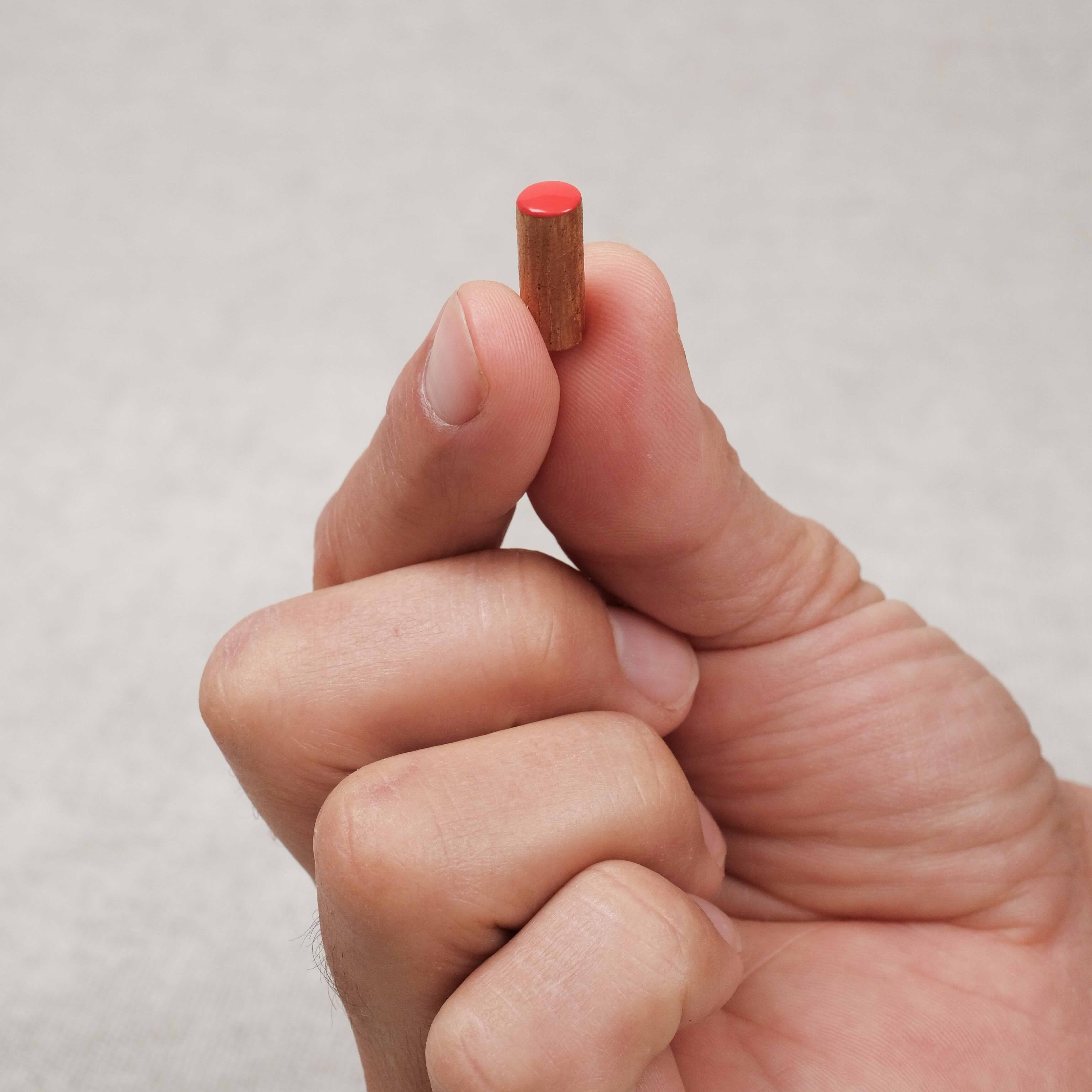main tenant un pion rouge en acacia en bois