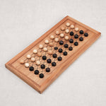 Plateau de jeu Fanorona en bois avec pions clairs et foncés alignés