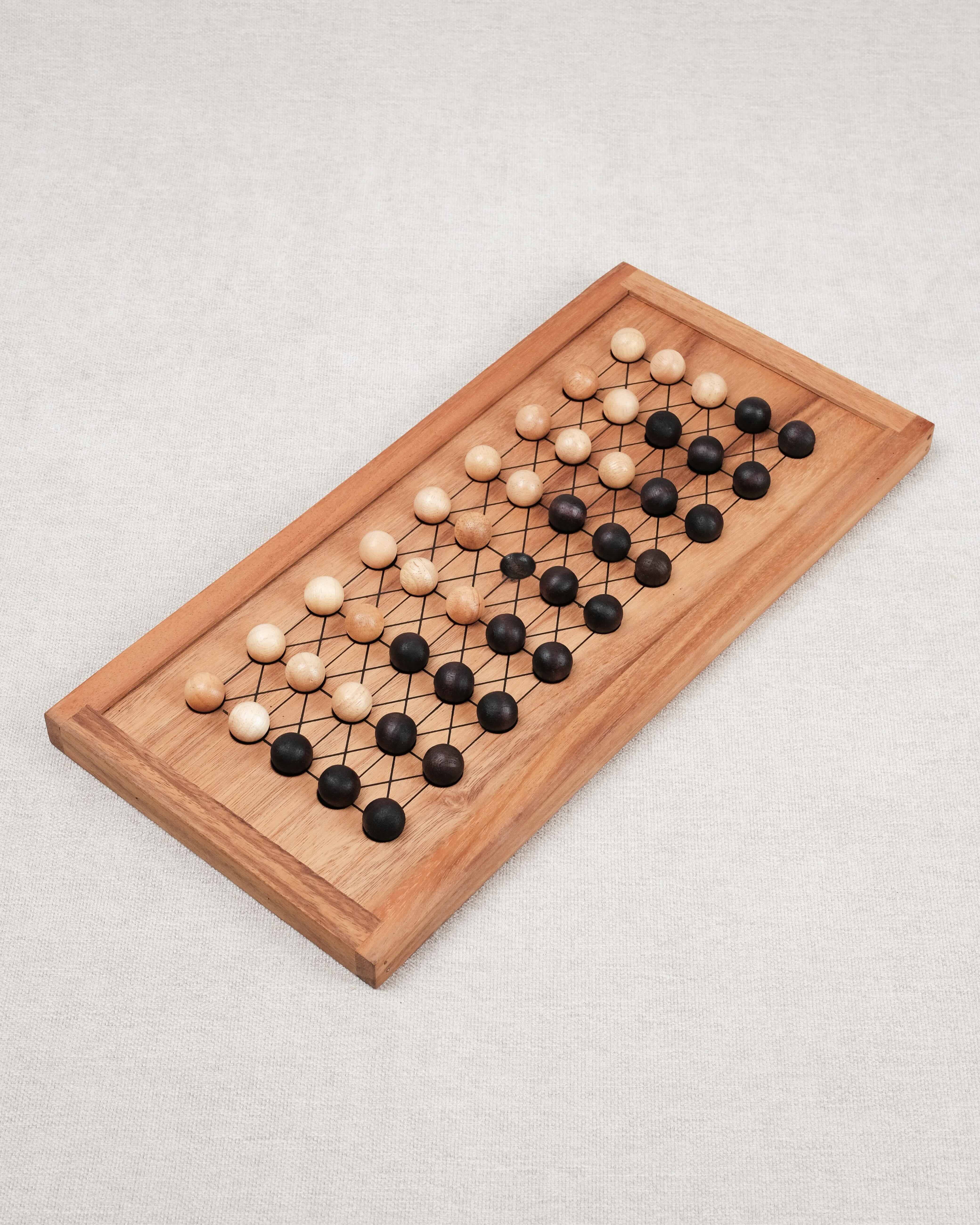 Plateau de jeu Fanorona en bois avec pions clairs et foncés alignés