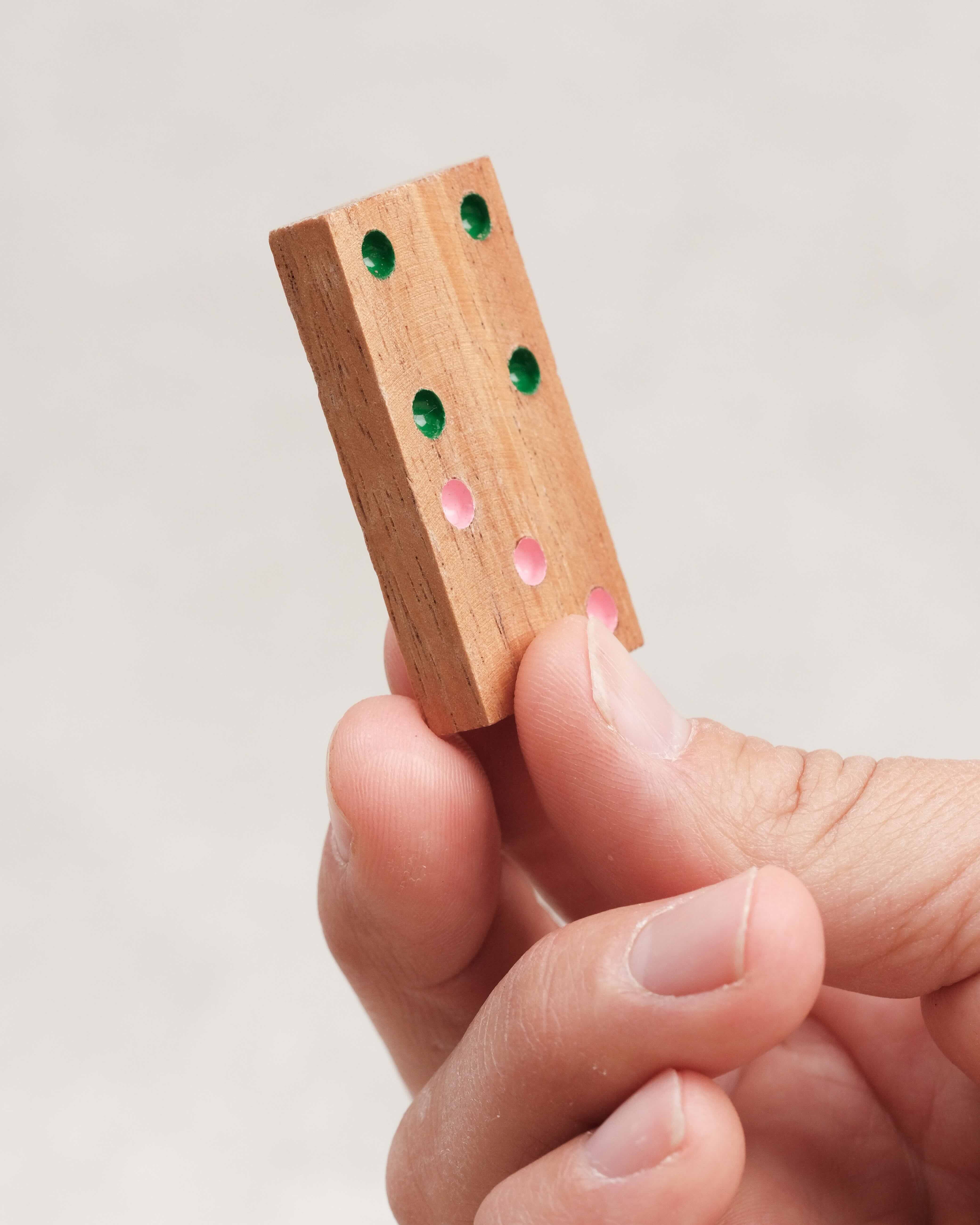 Pièce de domino en bois sérigraphié tenue en main