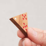 Pièce triangulaire gravée et colorée de Triomino tenue en main