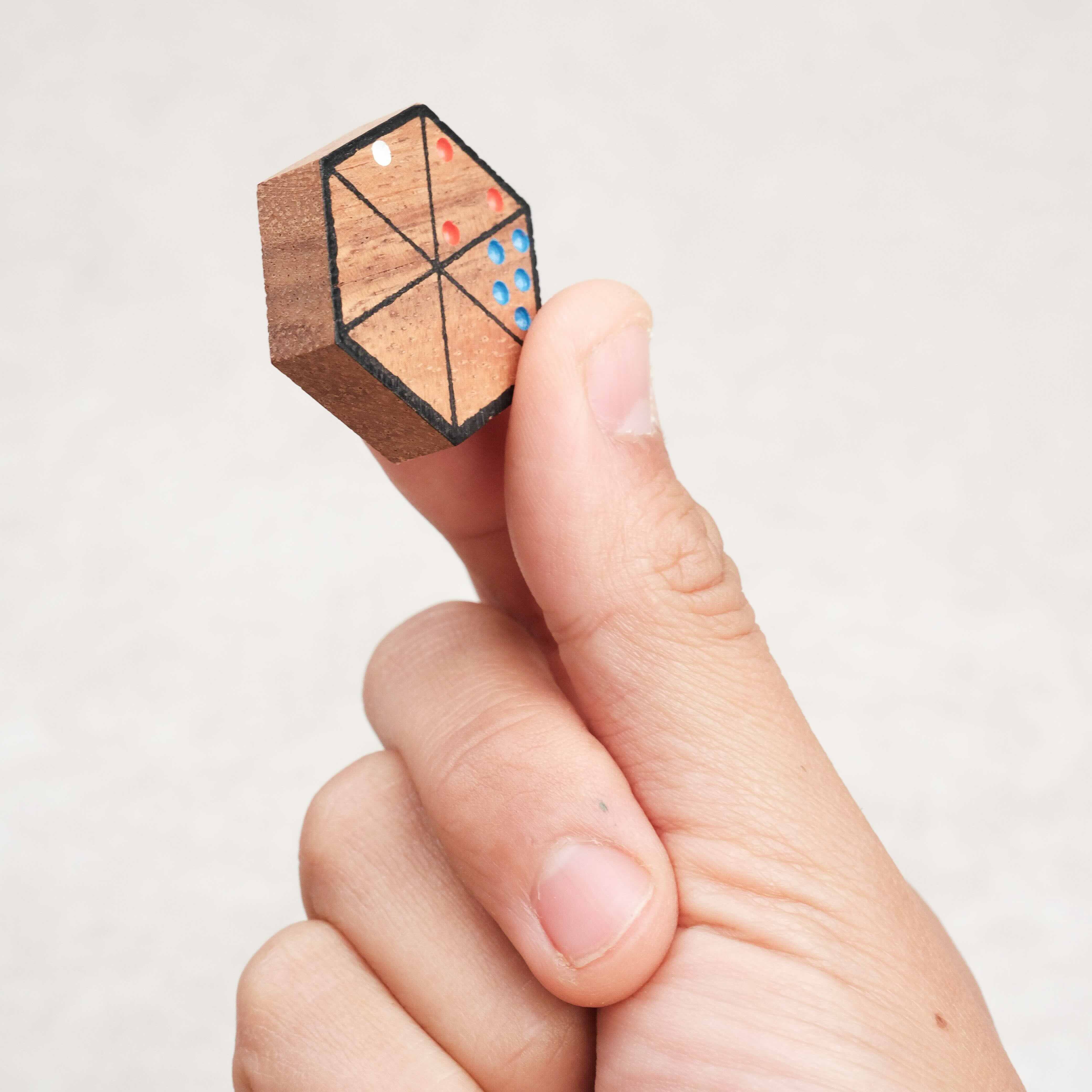 Pièce hexagonale sérigraphiée de l’Hexadomino tenue en main