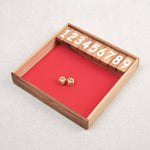 Plateau en bois du jeu Ferme la Boîte avec dés et chiffres numérotés.