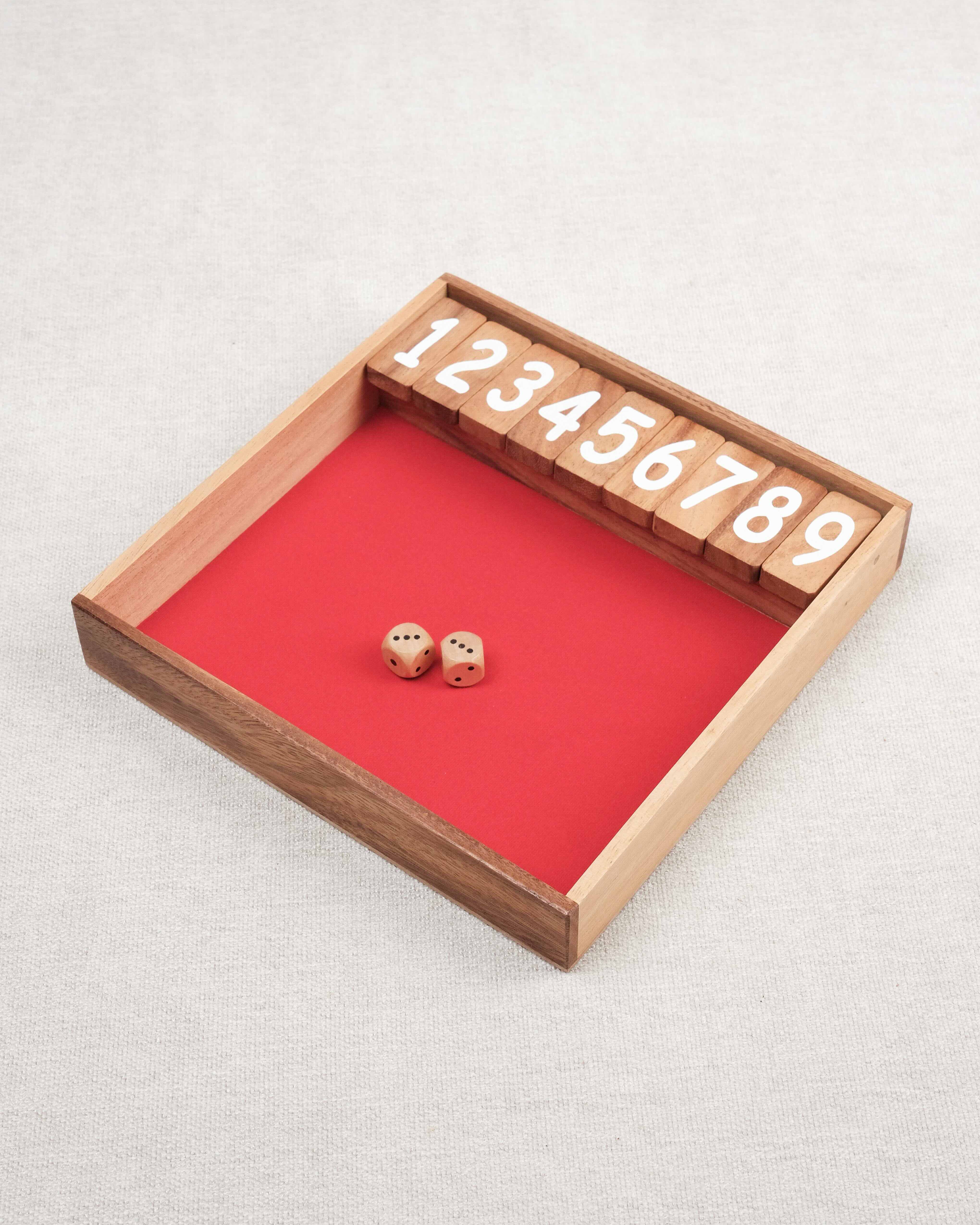 Plateau en bois du jeu Ferme la Boîte avec dés et chiffres numérotés.