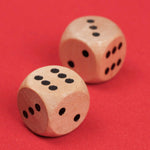 Gros plan sur deux dés en bois posés sur le plateau rouge.