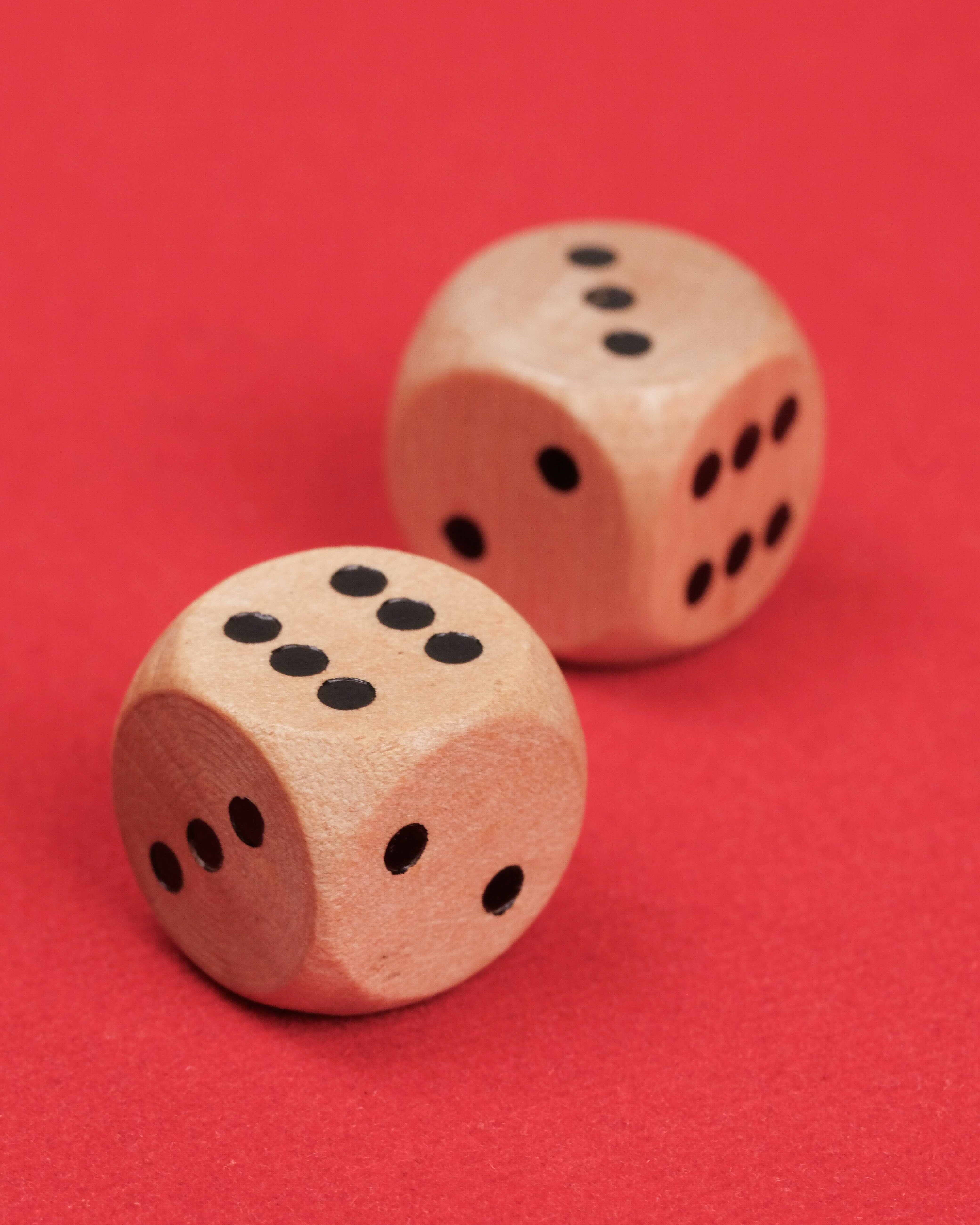 Gros plan sur deux dés en bois posés sur le plateau rouge.