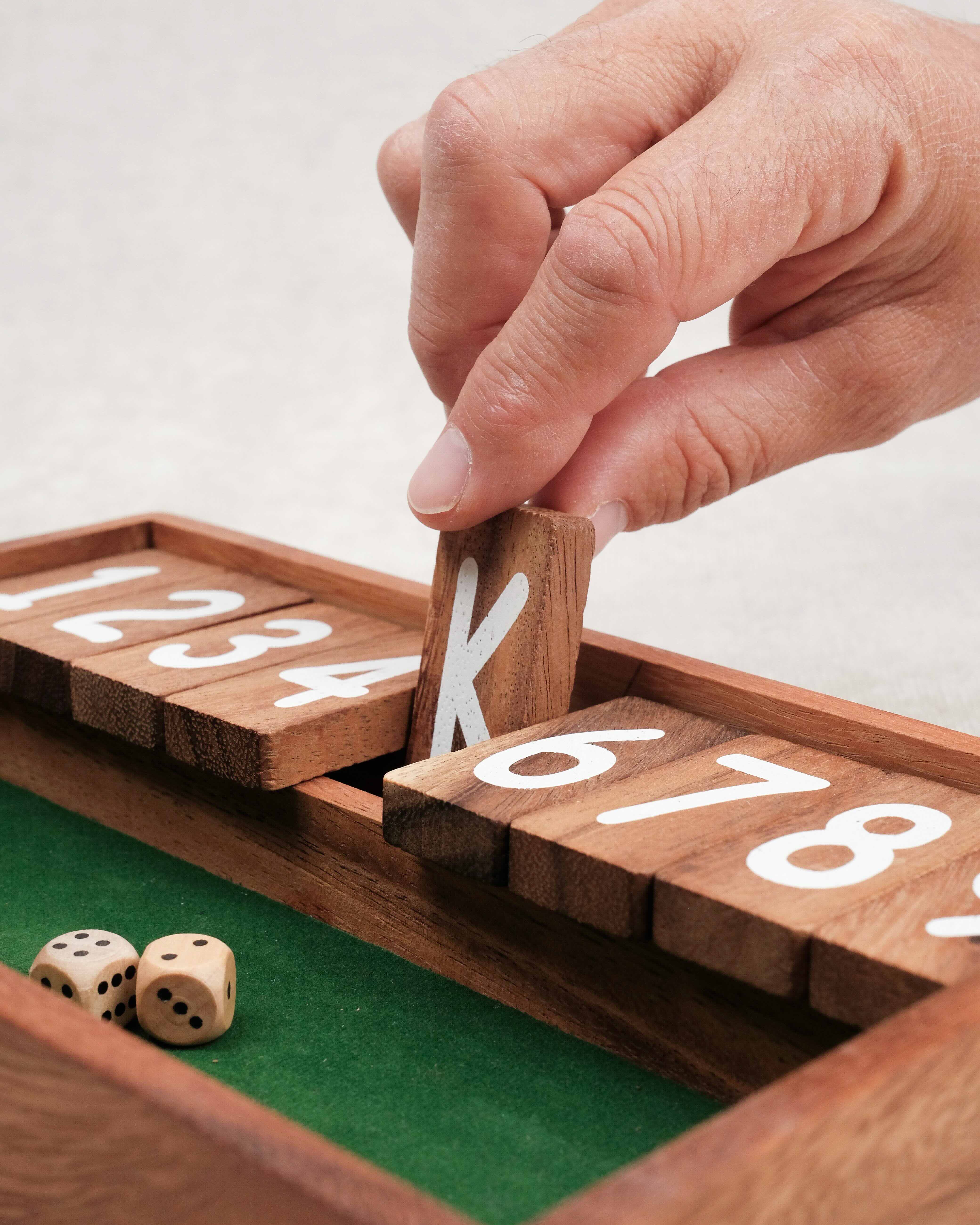 Main qui ferme une case numérotée sur le jeu Ferme la Boîte petit modèle.