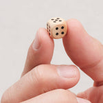 Main tenant un dé en bois du jeu Ferme la Boîte petit modèle.