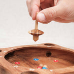 Main lançant la toupie sur La Giroulette en bois