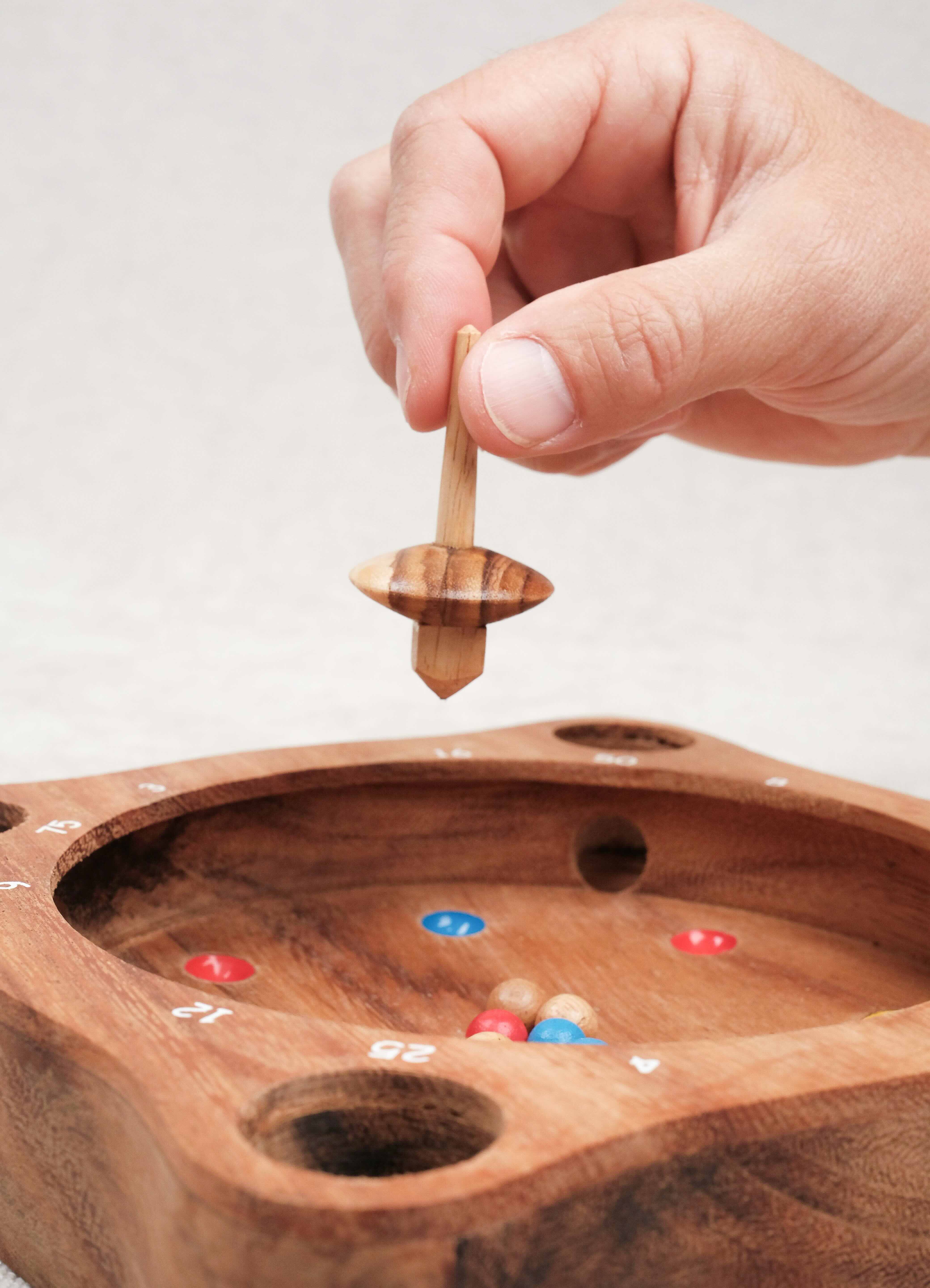 Main lançant la toupie sur La Giroulette en bois