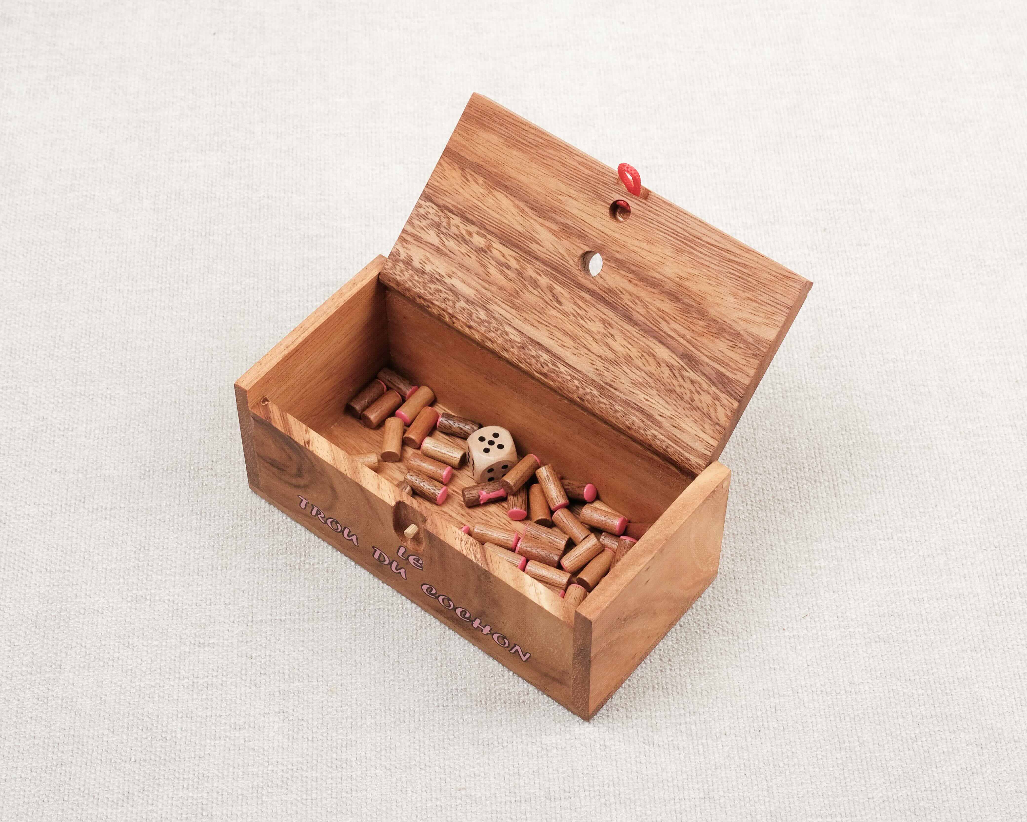 Coffret ouvert avec le dé et toutes les queues de cochon à l’intérieur