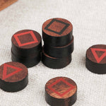 Gros plan sur les pions en bois avec symboles géométriques rouges.