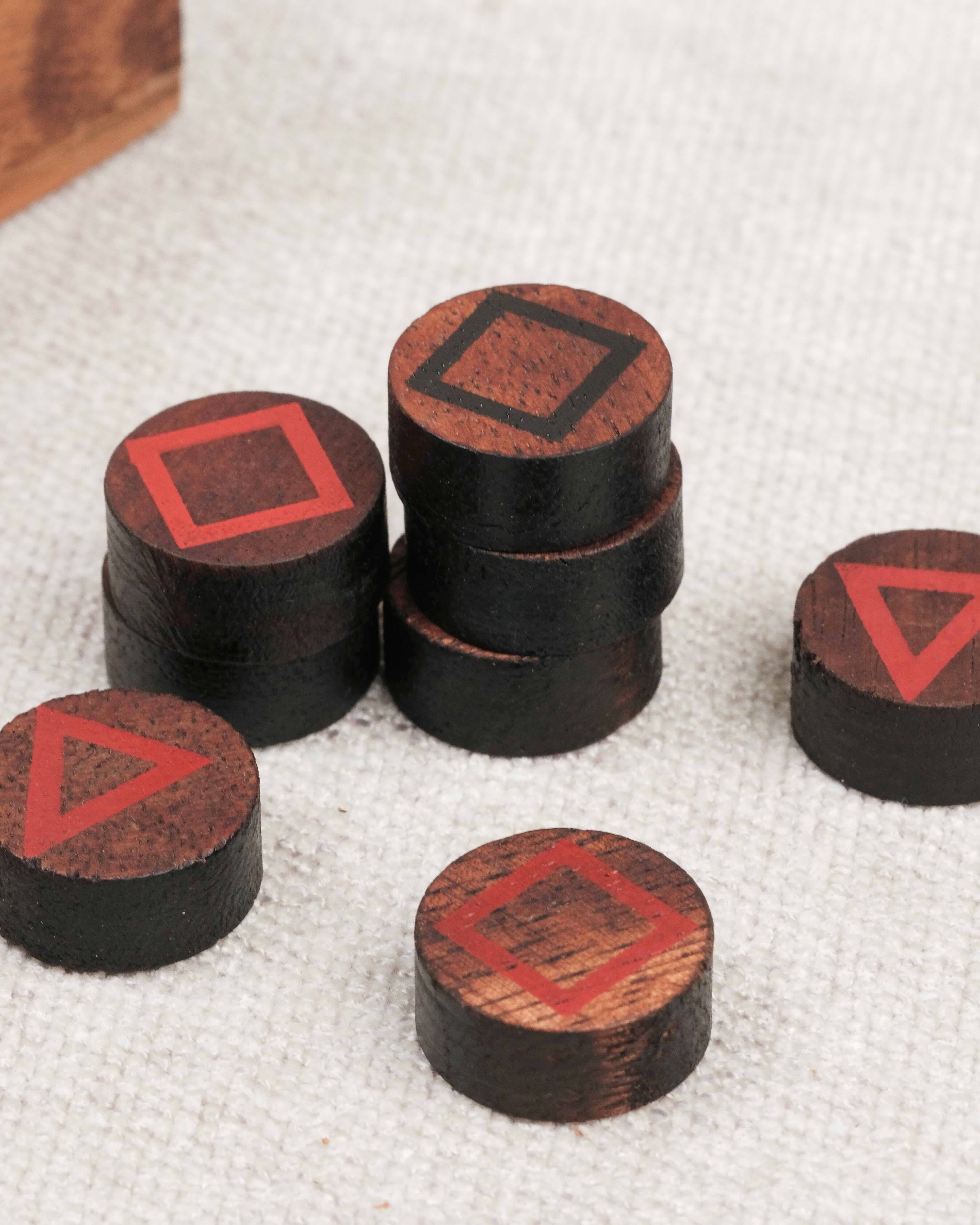 Gros plan sur les pions en bois avec symboles géométriques rouges.