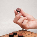 Main tenant un pion du jeu stratégique Mystrio.