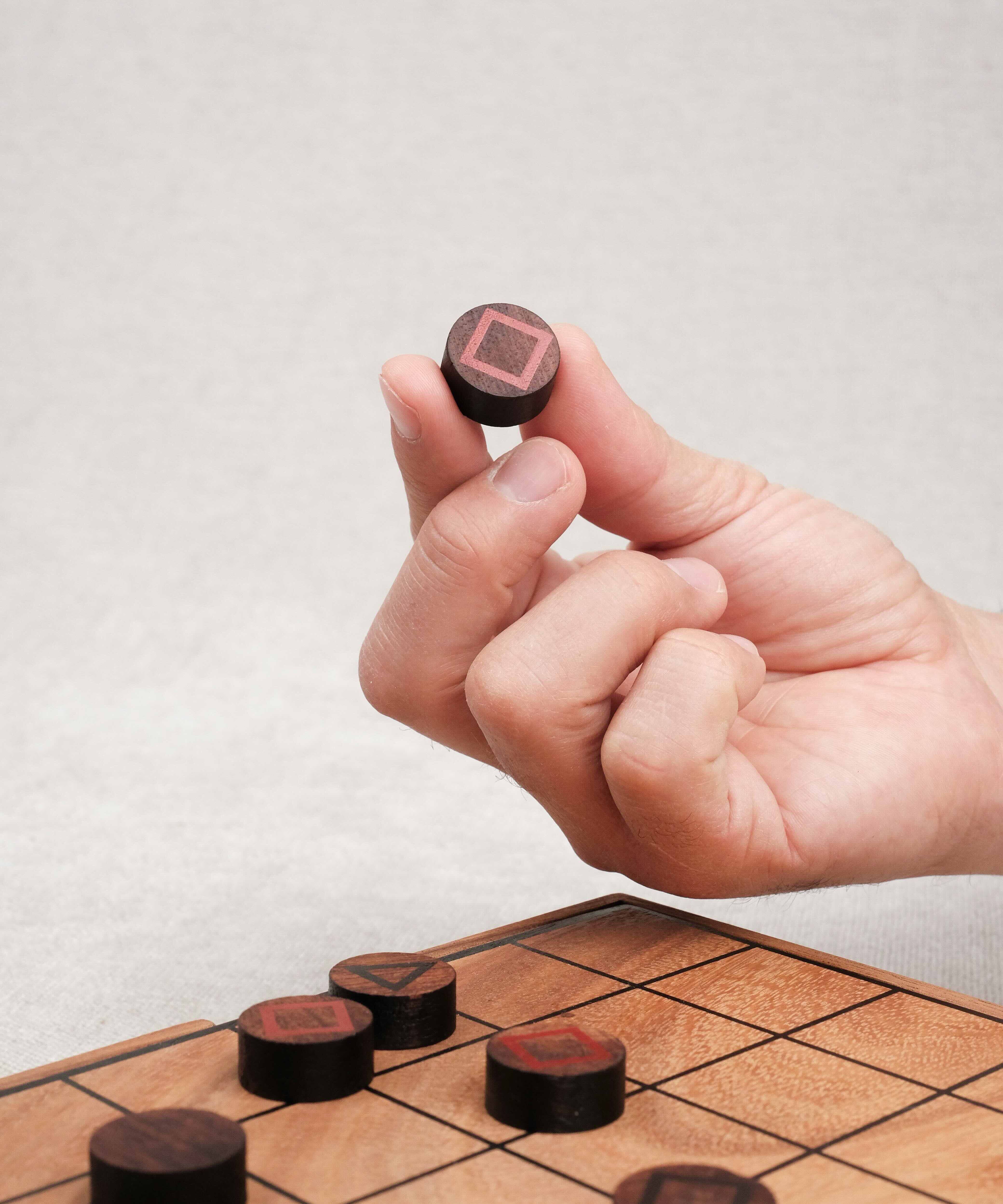 Main tenant un pion du jeu stratégique Mystrio.