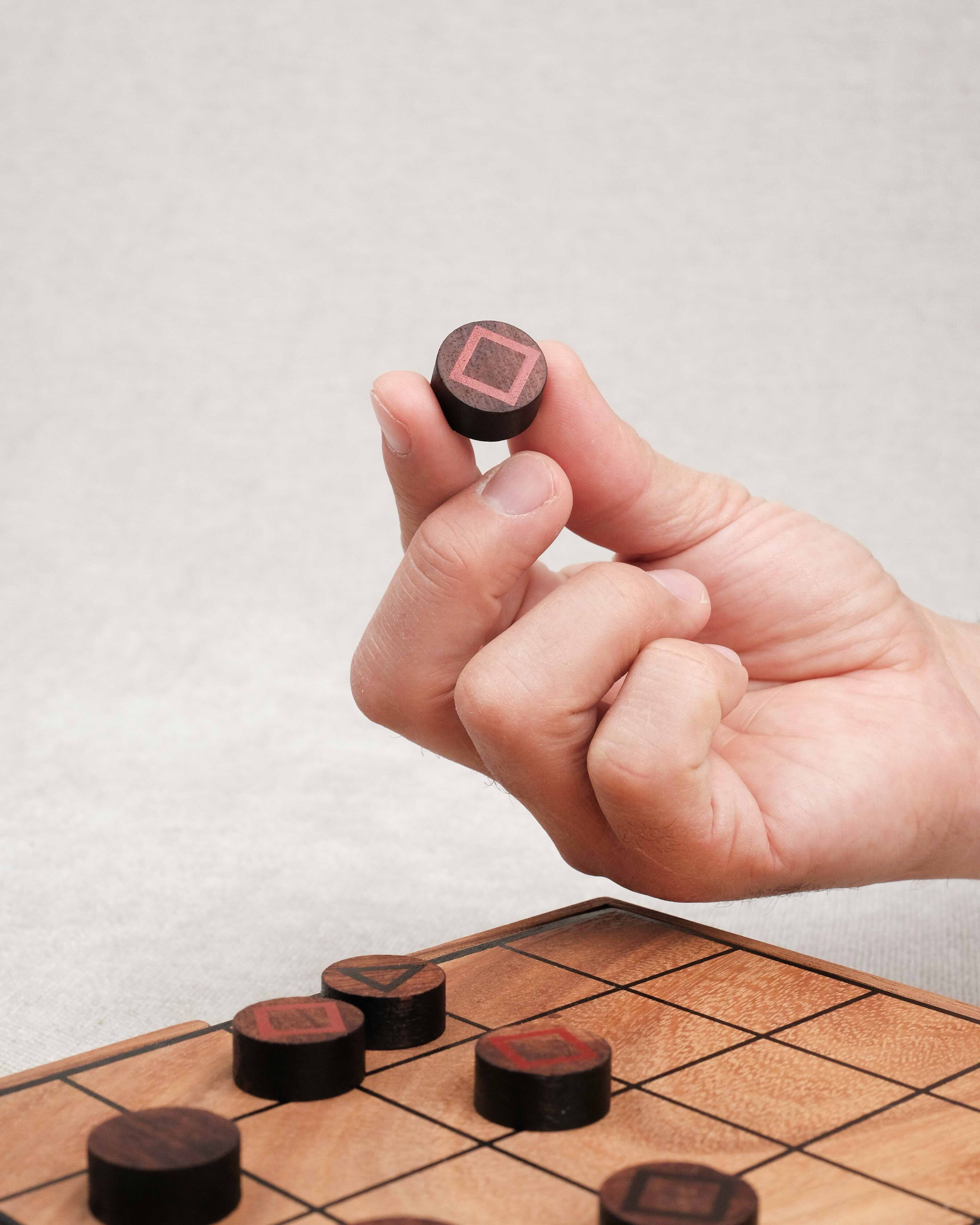 Main tenant un pion du jeu stratégique Mystrio.