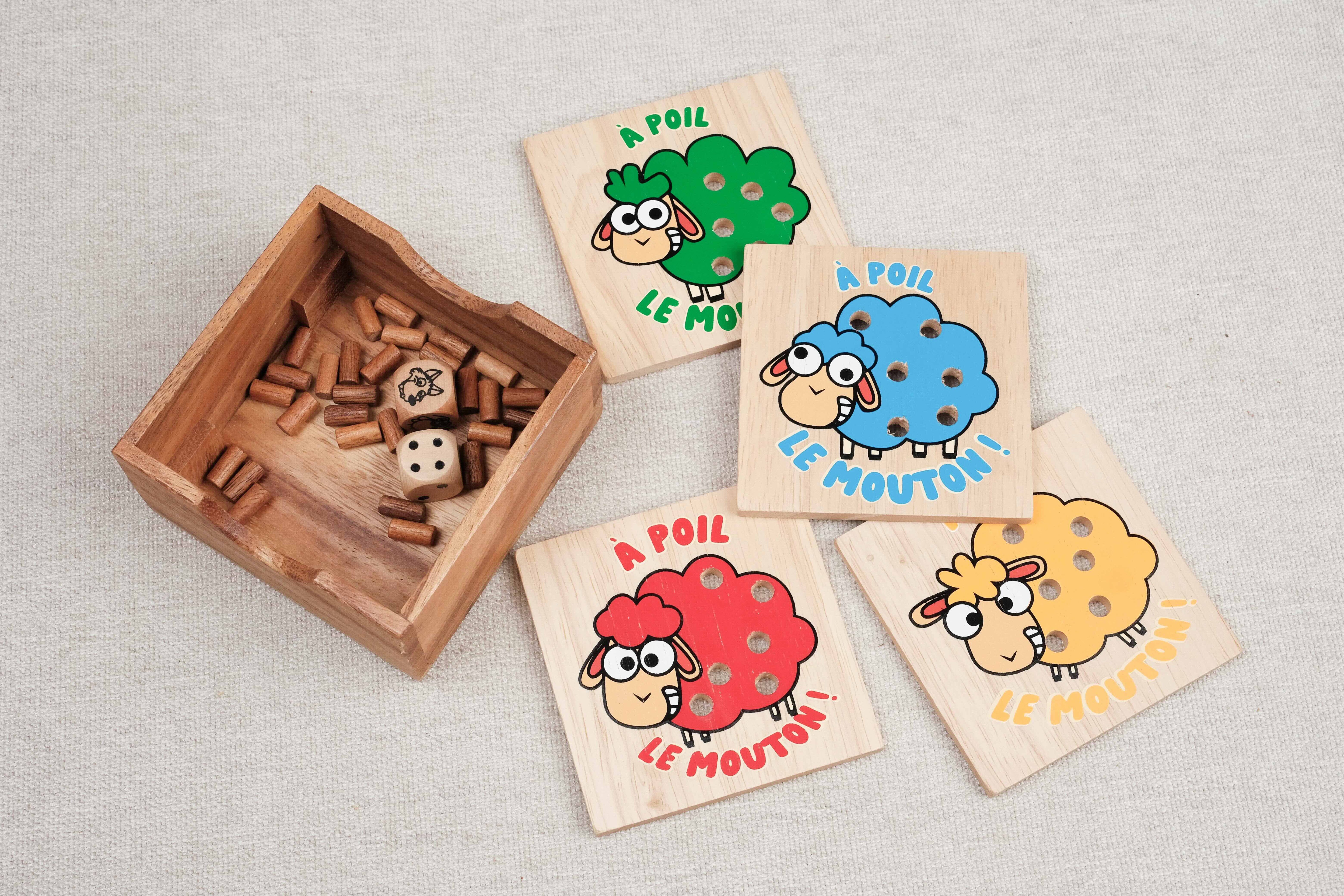 Coffret ouvert du jeu À Poil le Mouton avec plaquettes colorées et pions en bois.