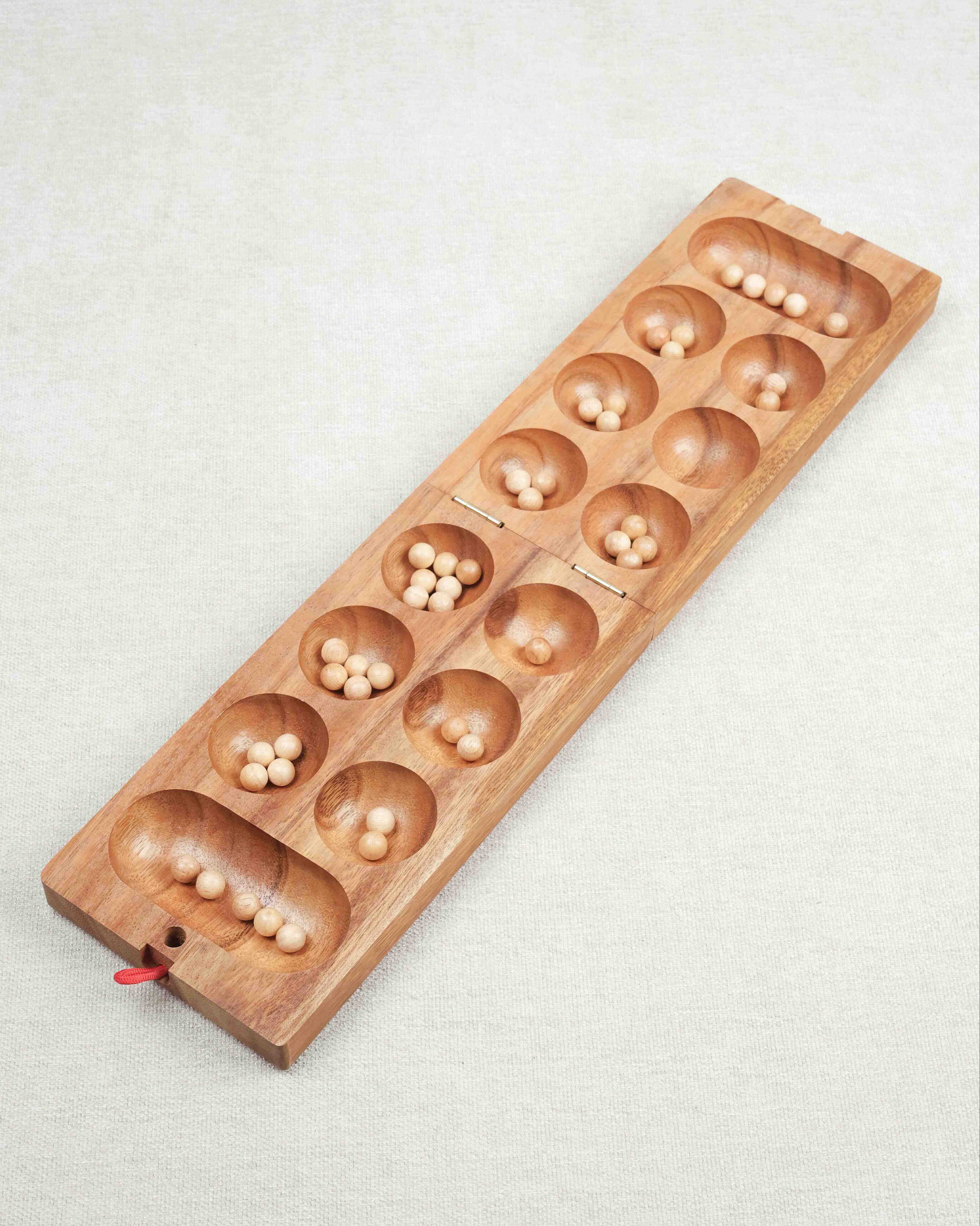 Plateau en bois de l’Awalé ouvert avec billes placées dans les alvéoles