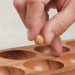 Main plaçant une bille dans une alvéole du Kalaha