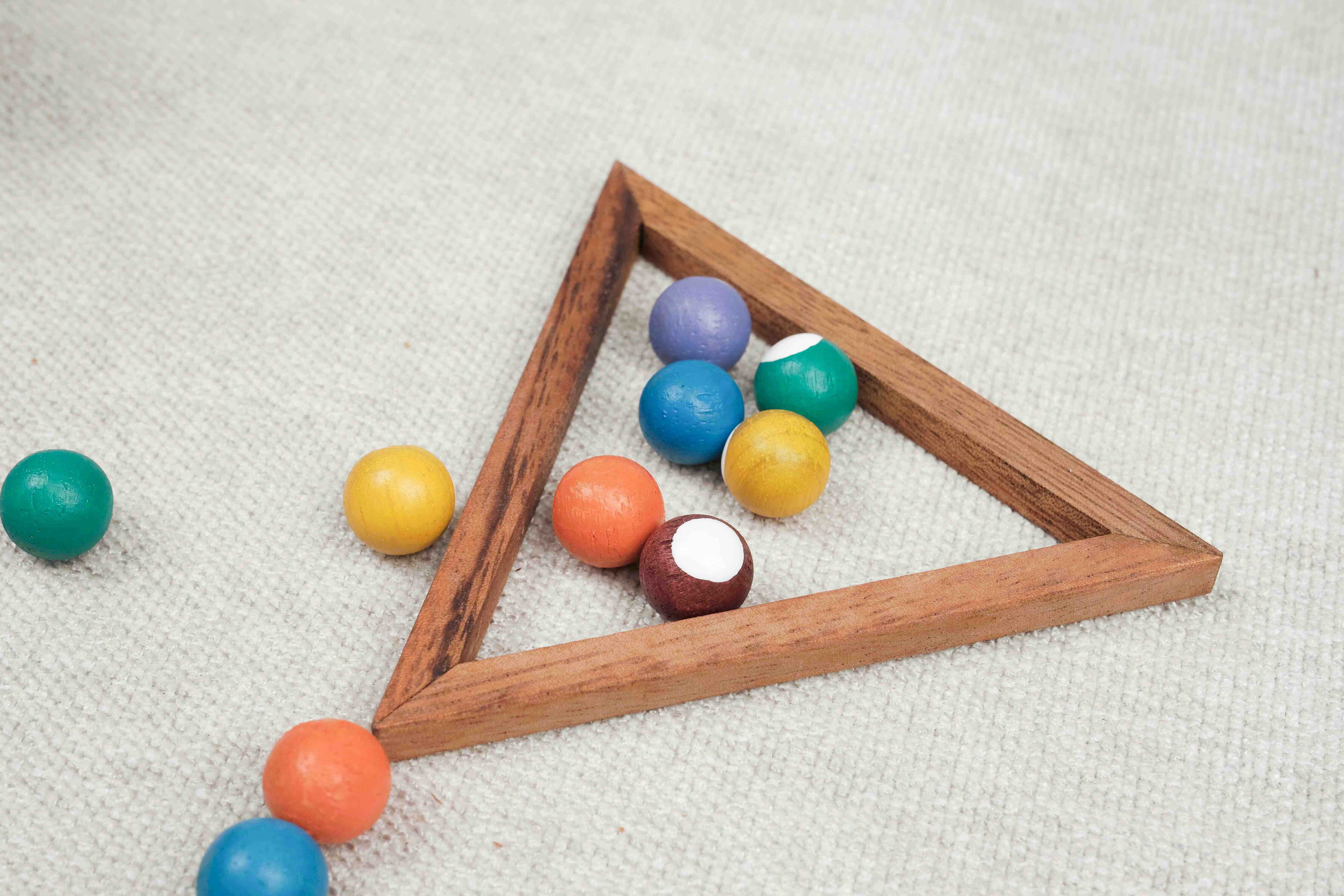 Gros plan sur les boules colorées du mini billard en bois avec triangle en bois sur fond blanc