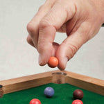 Main posant une bille colorée sur le mini billard
