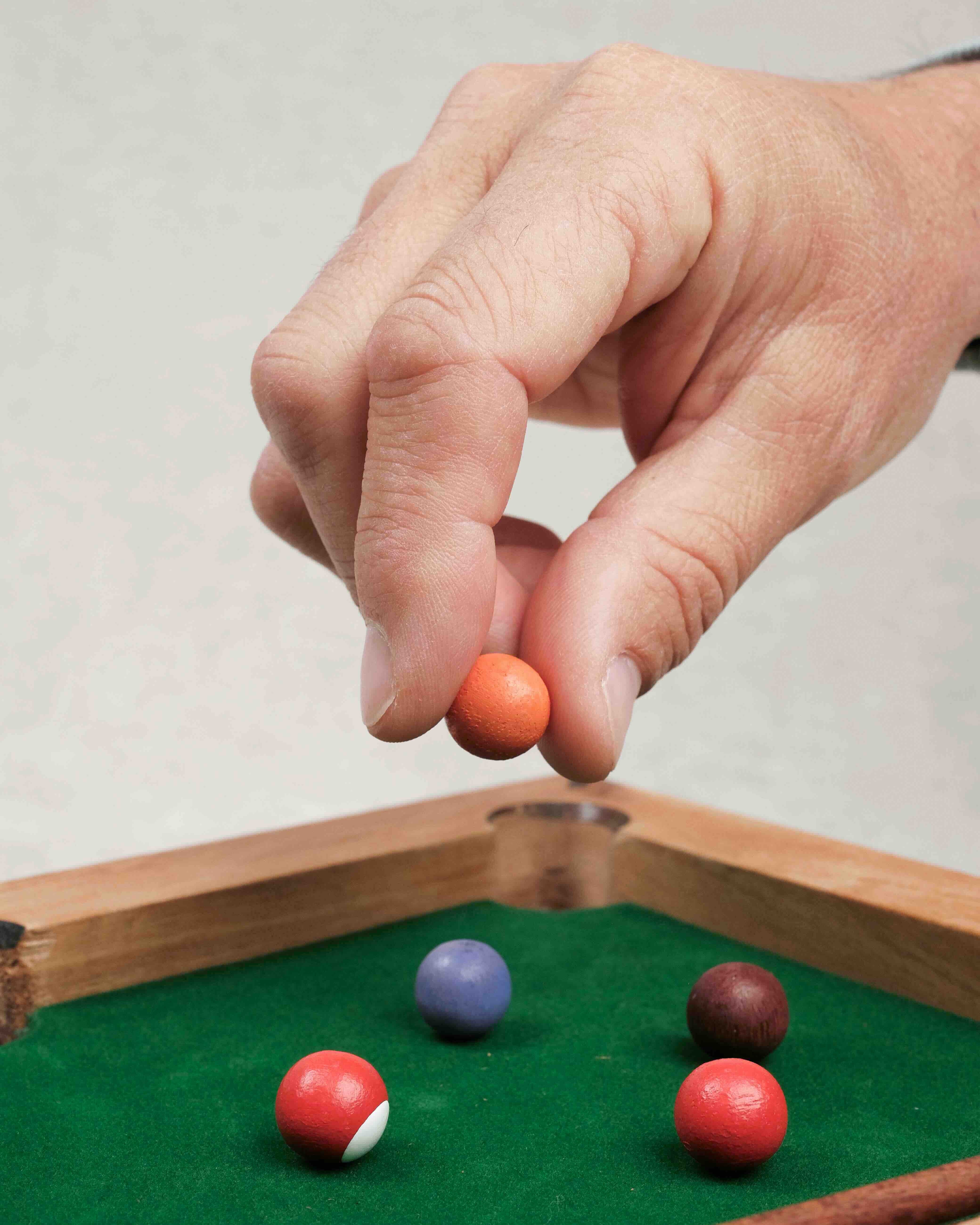 Main posant une bille colorée sur le mini billard