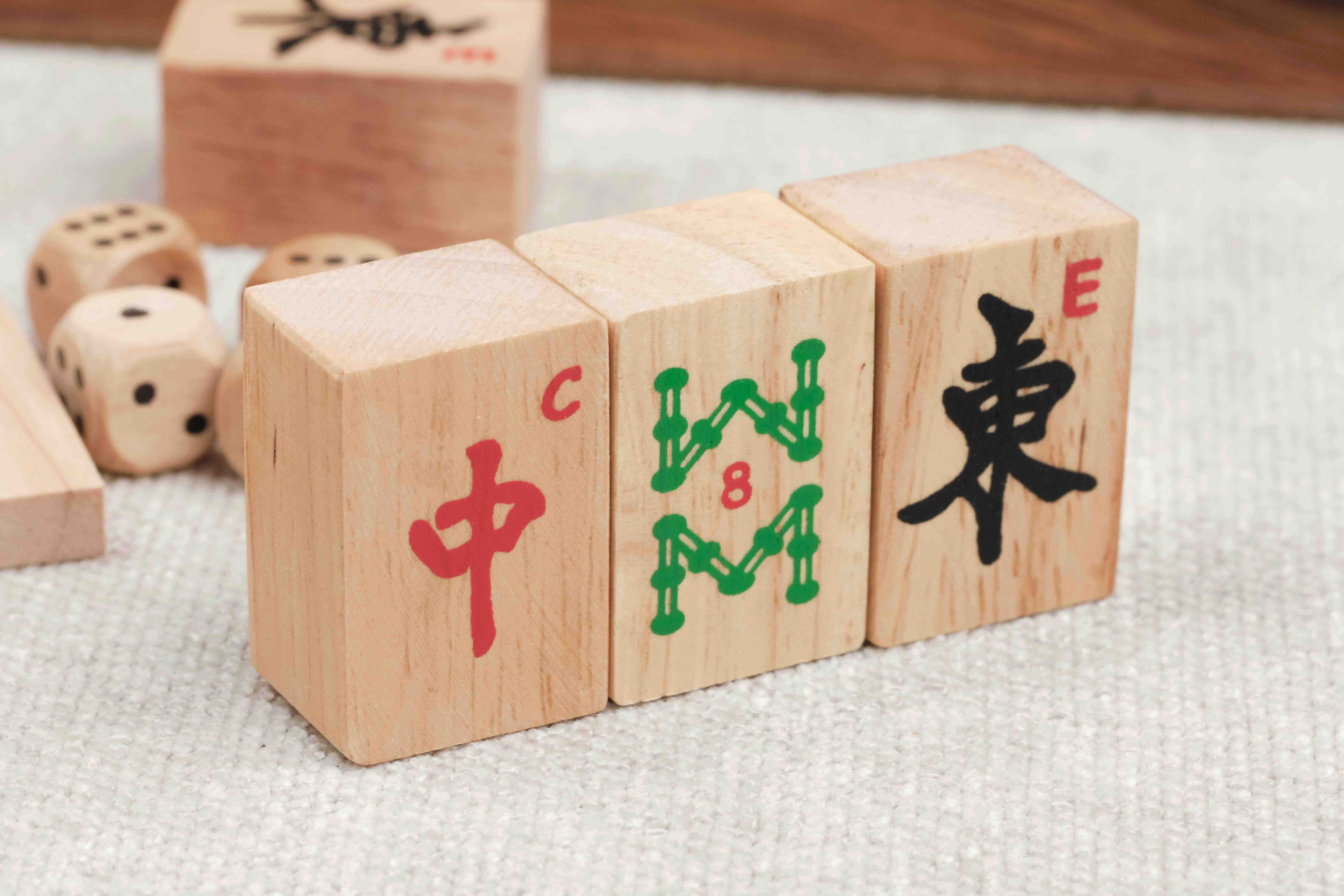 Trois tuiles de Mah-Jong et dés en bois posés sur une table