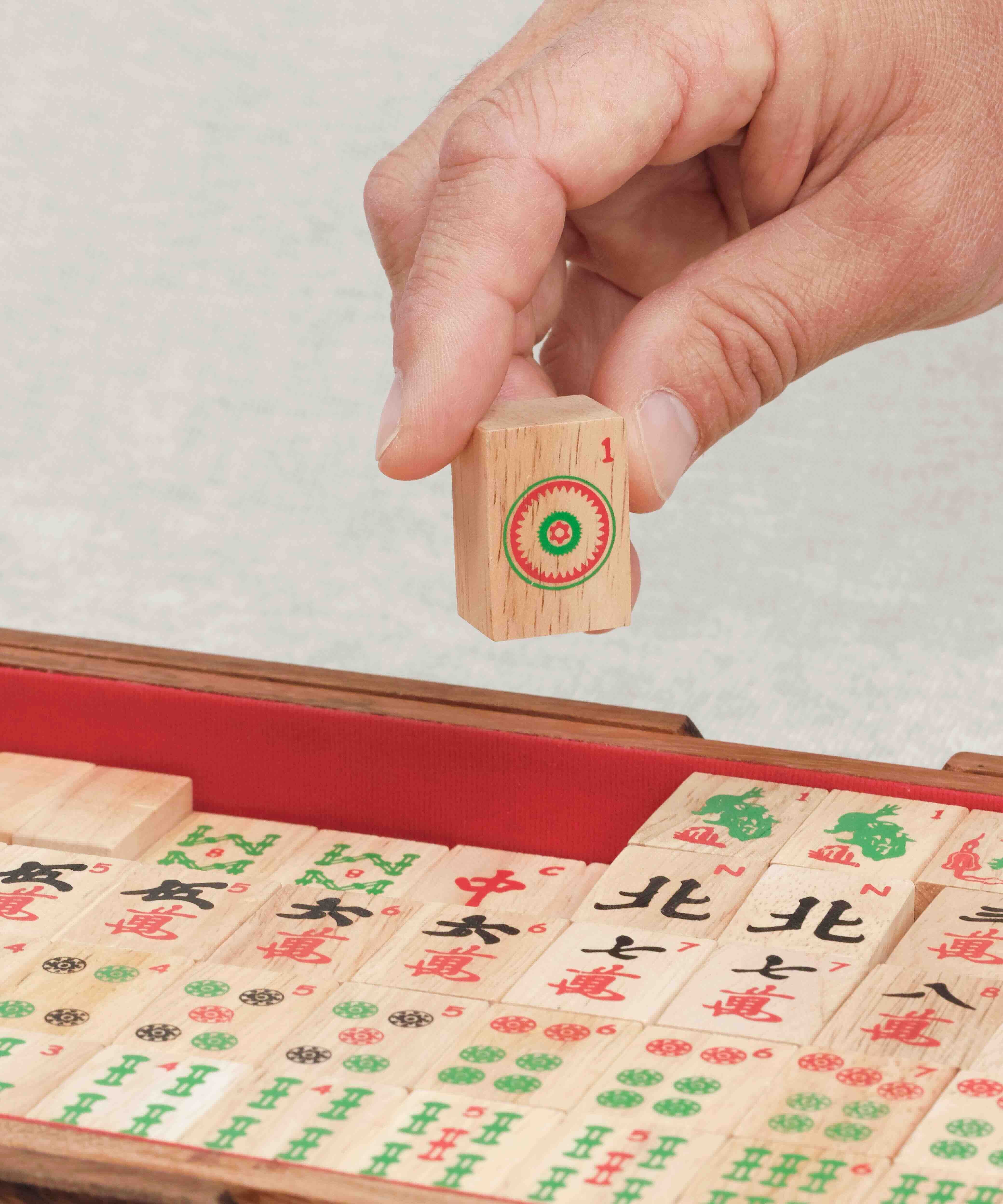 Main tenant une tuile sérigraphiée de Mah-Jong