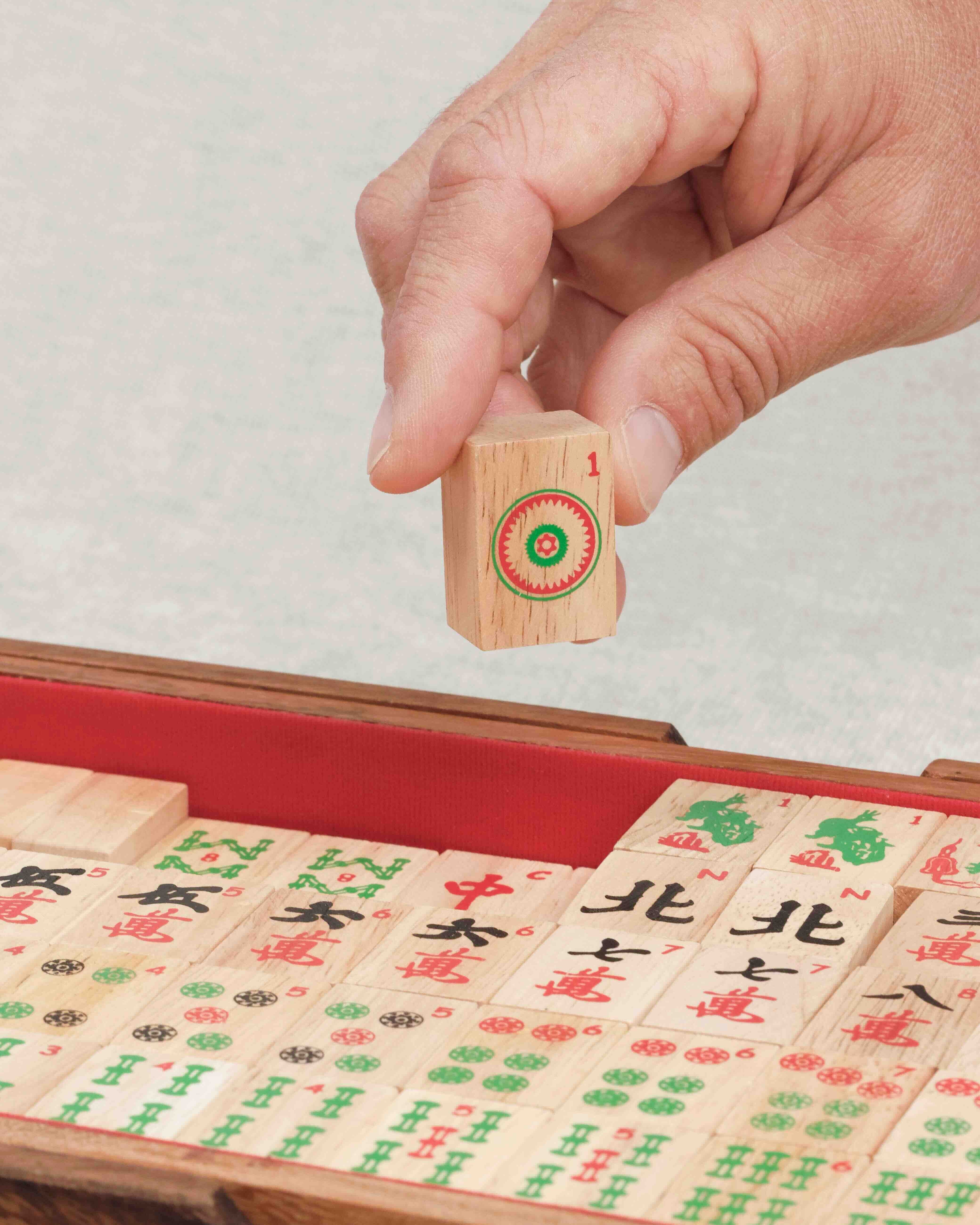 Main tenant une tuile sérigraphiée de Mah-Jong