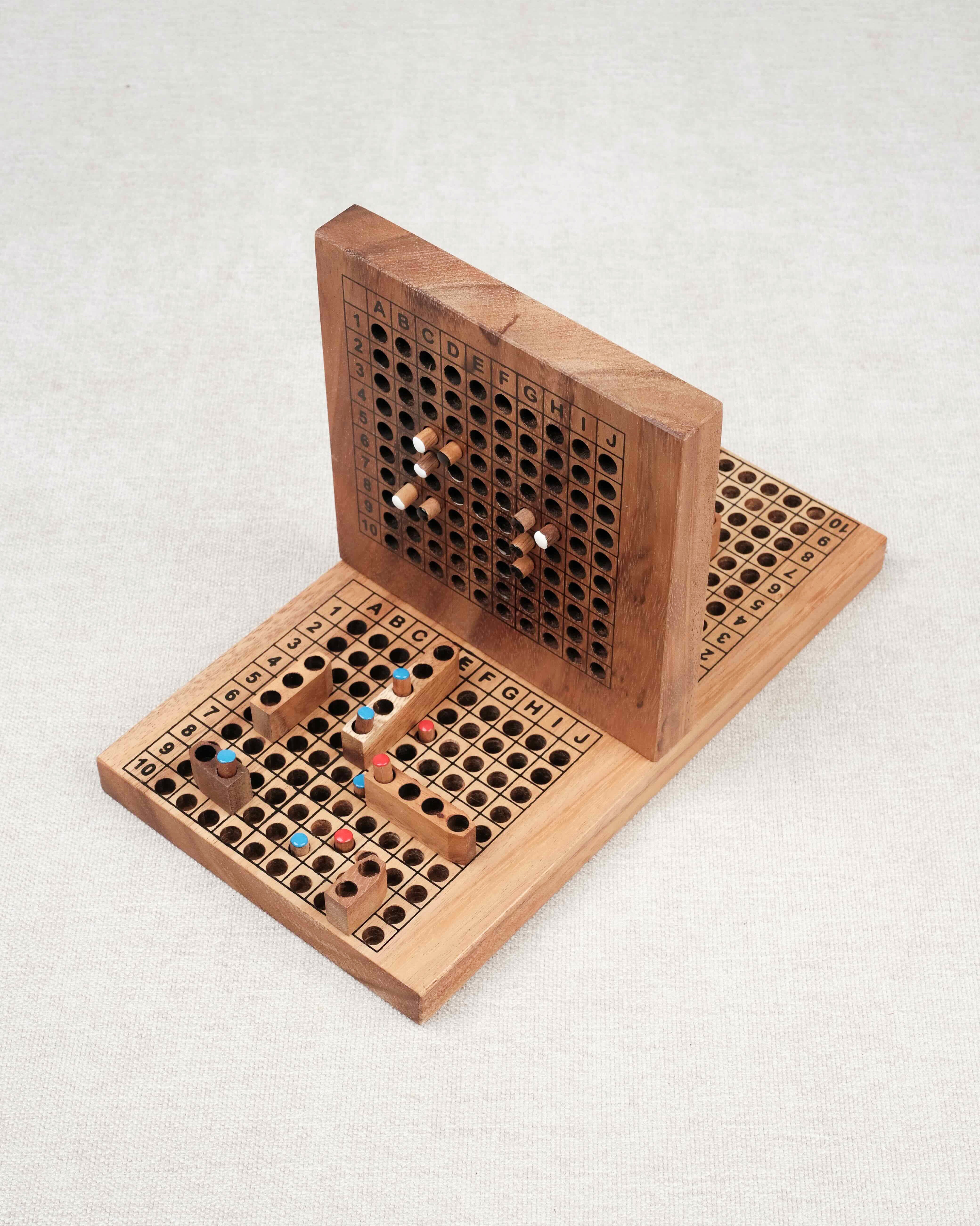 Plateau de bataille navale en bois ouvert avec pions colorés insérés