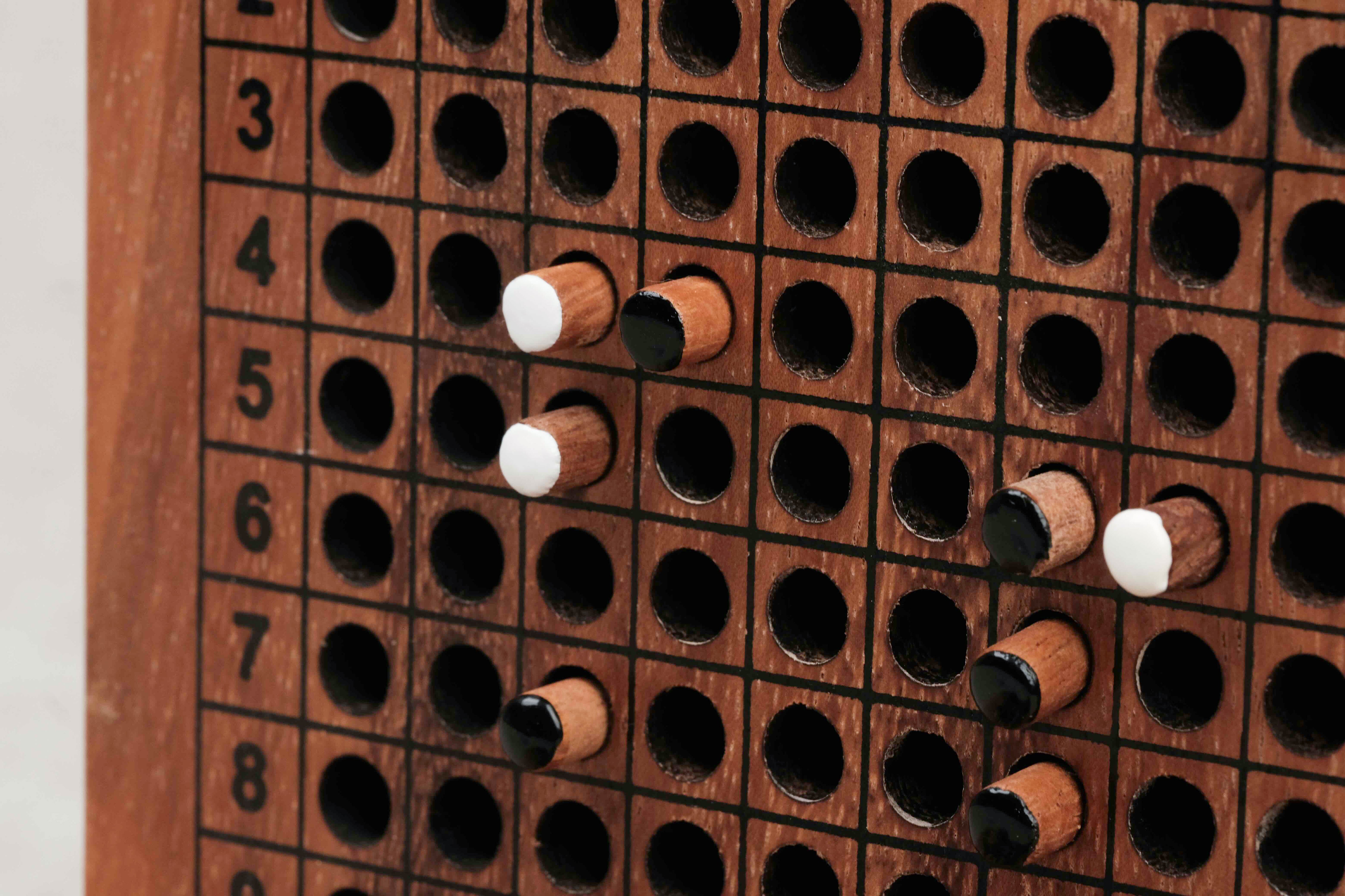 Plateau vertical avec grille de bataille navale et pions blancs et noirs insérés