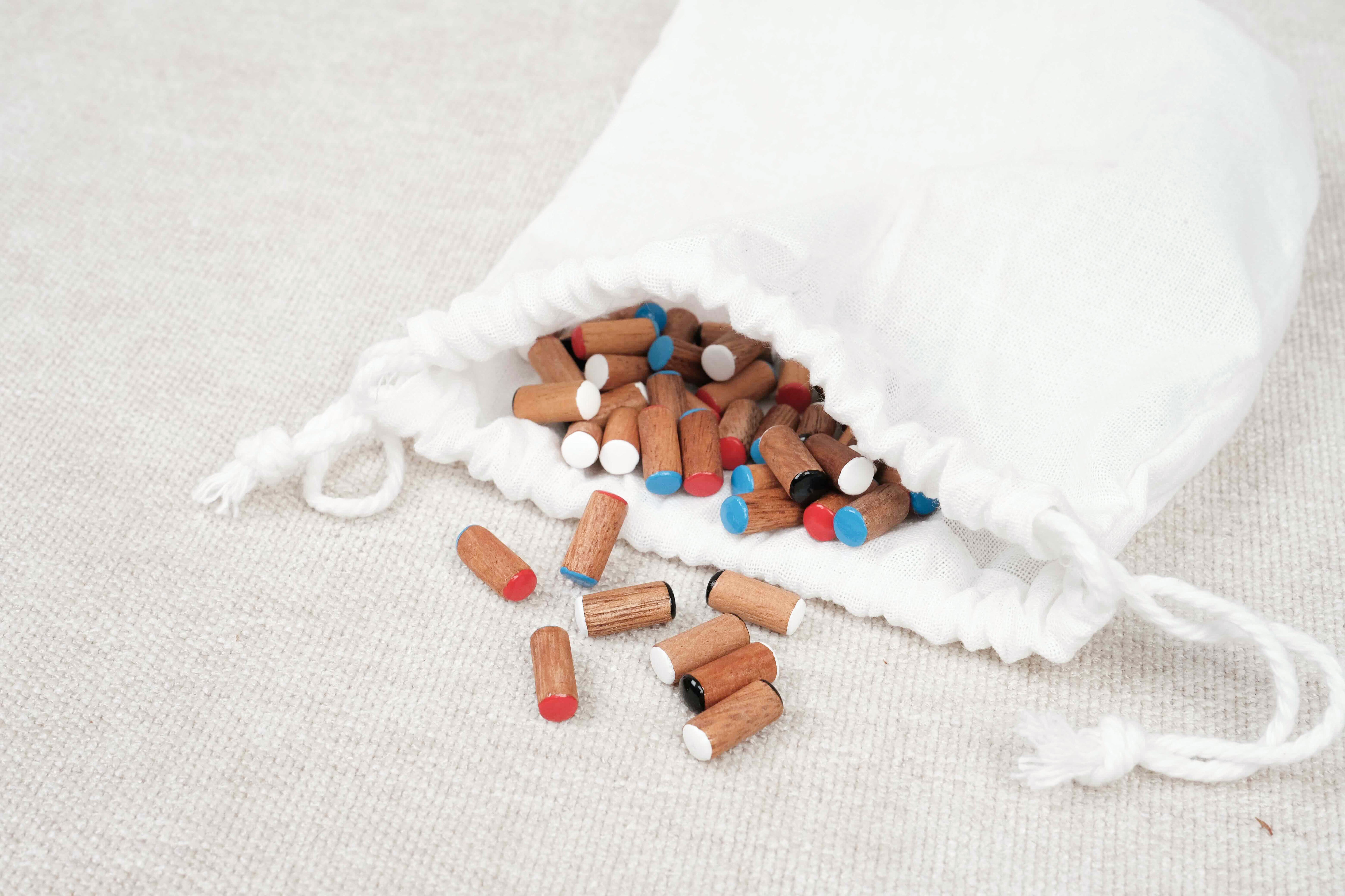 Pochon en tissu blanc avec pions colorés et navires en bois